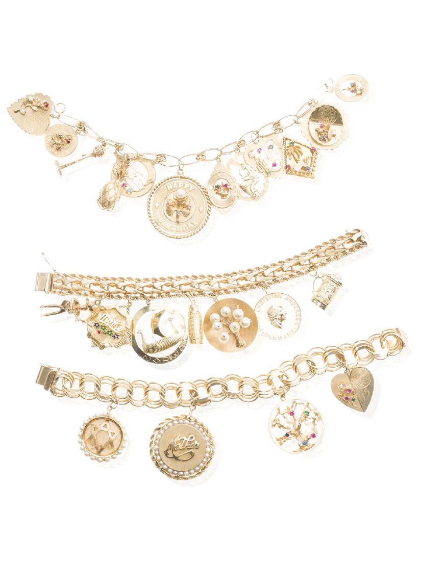 Three gold charm bracelets: 14k yellow gold Including three chain bracelets suspending twenty-three various charms many set with gemstones and cultured pearls Longest: 8 1/4 221.0 grams 3 pieces
