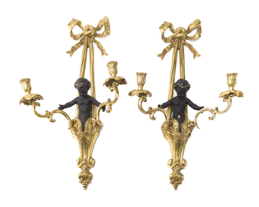 A pair of bronze figural wall sconces: Late 19th/early 20th century Each two-light scone with designed with a putto holding aloft to candle holders, 2 pieces Each: 22" H x 12.5" W x 6" D