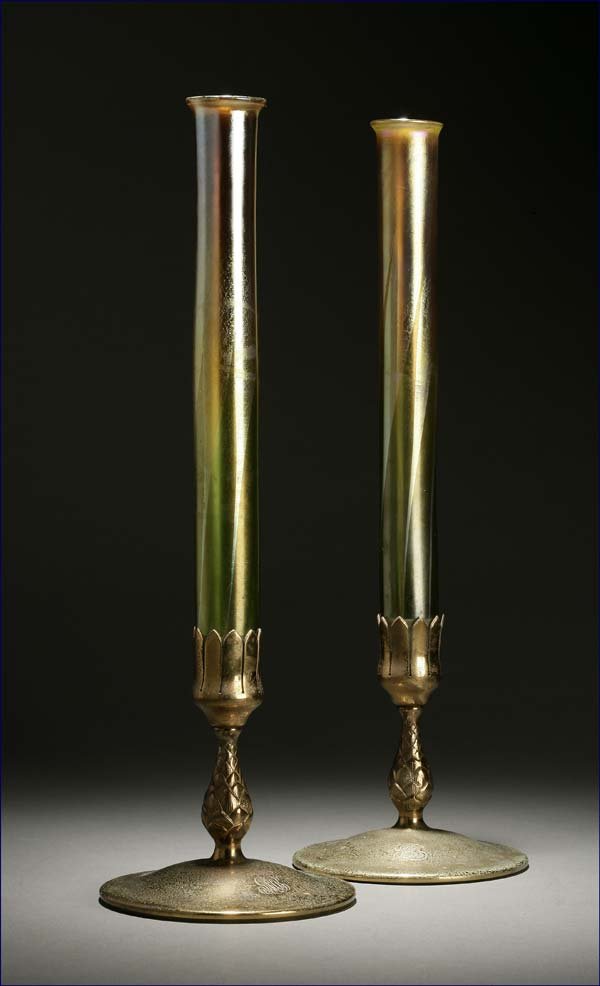 Pair Tiffany Favrile glass & bronze bud vases: circa 1910, the vases signed ''L.C.T'', the bases stamped ''Tiffany Studios/New York/1043'', each with flared rim above an iridescent cylindrical body swirled with pulled green leaves, on a pineapple