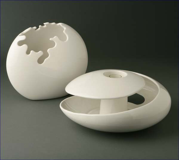 Two Raymor white-glazed pottery vases: second half 20th century, one with Raymor mark, the other bearing original Raymor label, one circular with asymmetric waved aperture, the other of circular spiral design with central glass bud vase, t