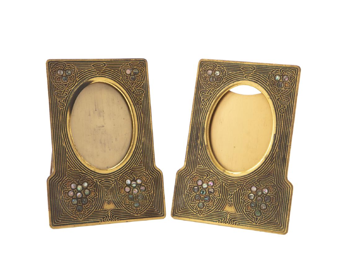 A pair of Tiffany Studios "Abalone" gilt-bronze picture: First quarter 20th century Each stamped: Tiffany Studios / New York / 1171 Each in the "Abalone" pattern with oval 5.325" H x 4" W openings Each: 10.25" H x 7.25" W