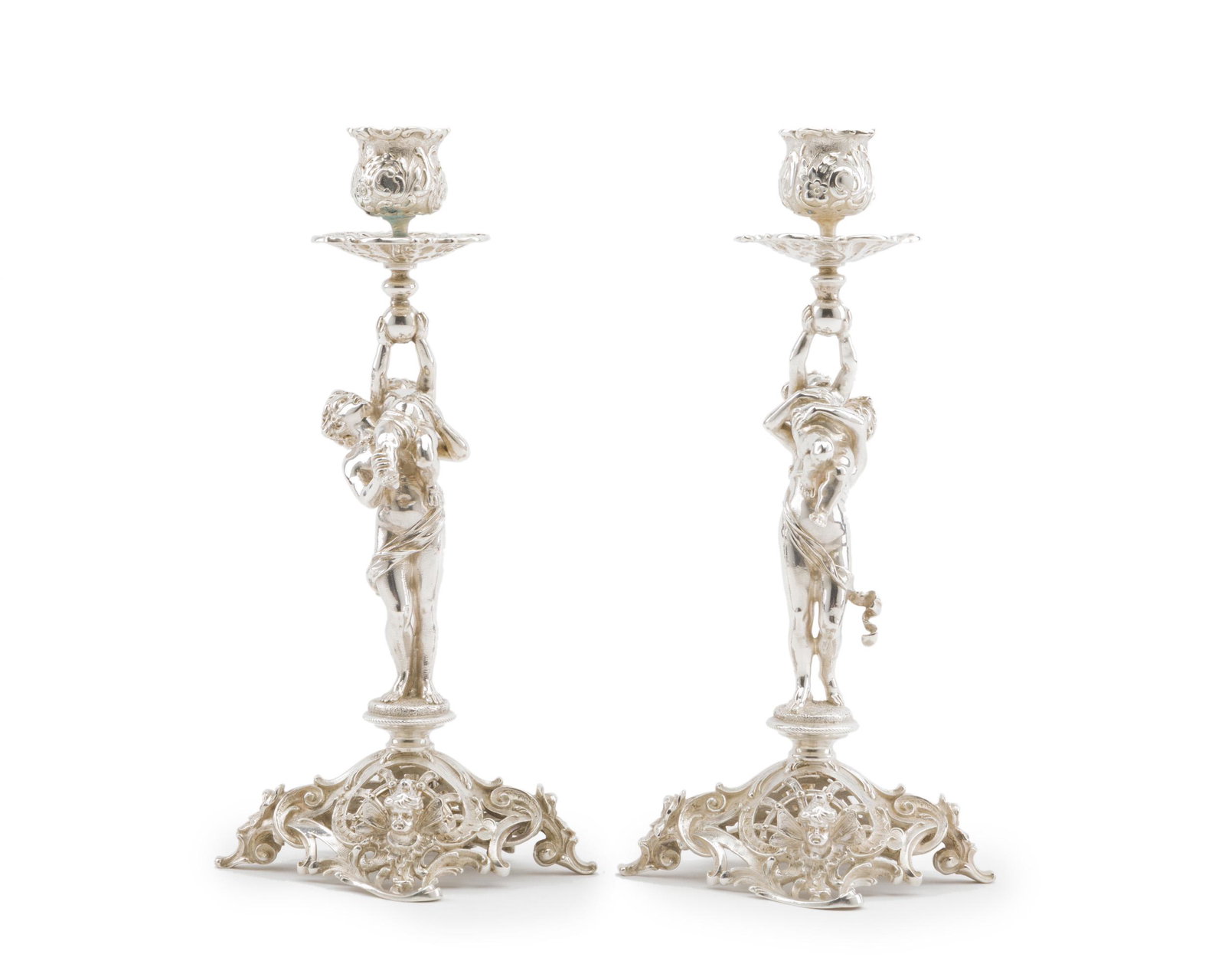 A pair of German Bruckmann & Söhne 800 silver: Post-1886 Each stamped with the crescent and crown mark, further stamped 800 and for Bruckmann & Söhne Each repoussé bobeche over a figural standard of Venus and Cupid raised on an ope