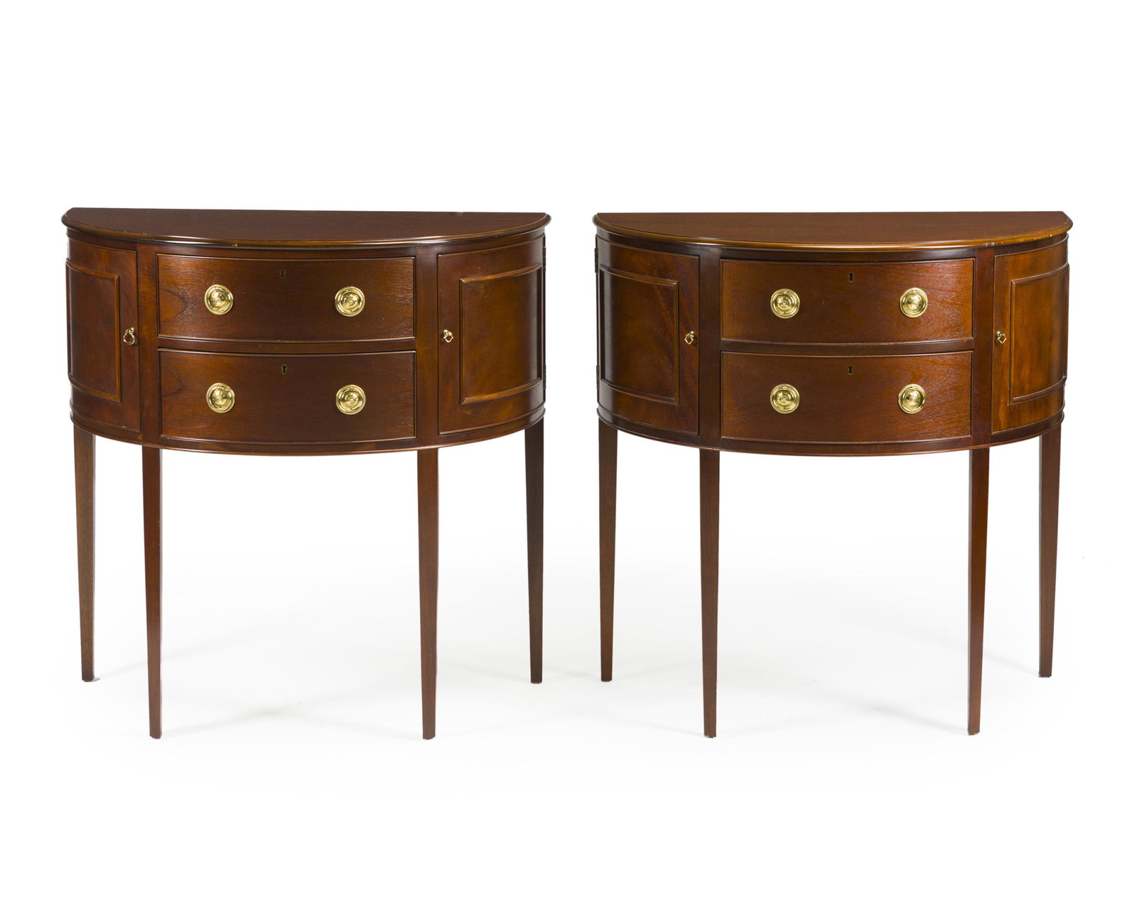 A pair of demi-lune console tables: Second half 20th century Each with metal tag: Baker Furniture / Historic Charleston Reproduction Each demi-lune console with two short drawers flanked by two side cabinets raised on tapering legs, 2 p