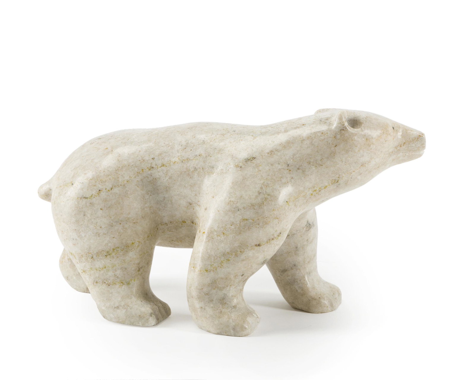 A carved stone polar bear, Clyde River: Late 20th century Standing polar bear in white variegated stone, attached tag indicates artist's name illegibly 7" H x 5" W x 13" D