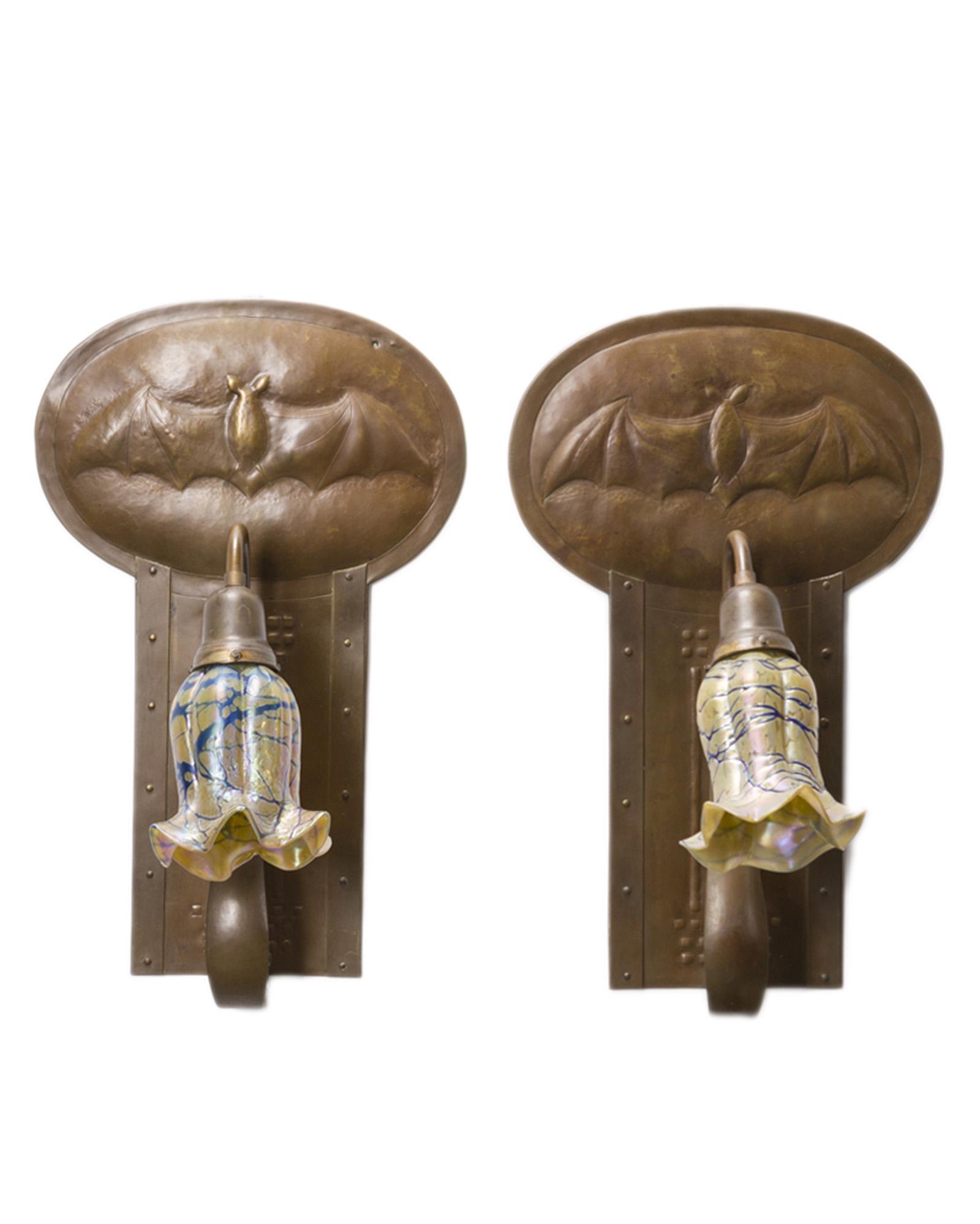 A pair of Glasgow School copper bat sconces: Late 19th/early 20th century, Scotland Apparently unmarked Each molded bronze oval plaque with stylized bat over an Arts & Crafts rectangular panel issuing a scrolled arm suspending a single lig