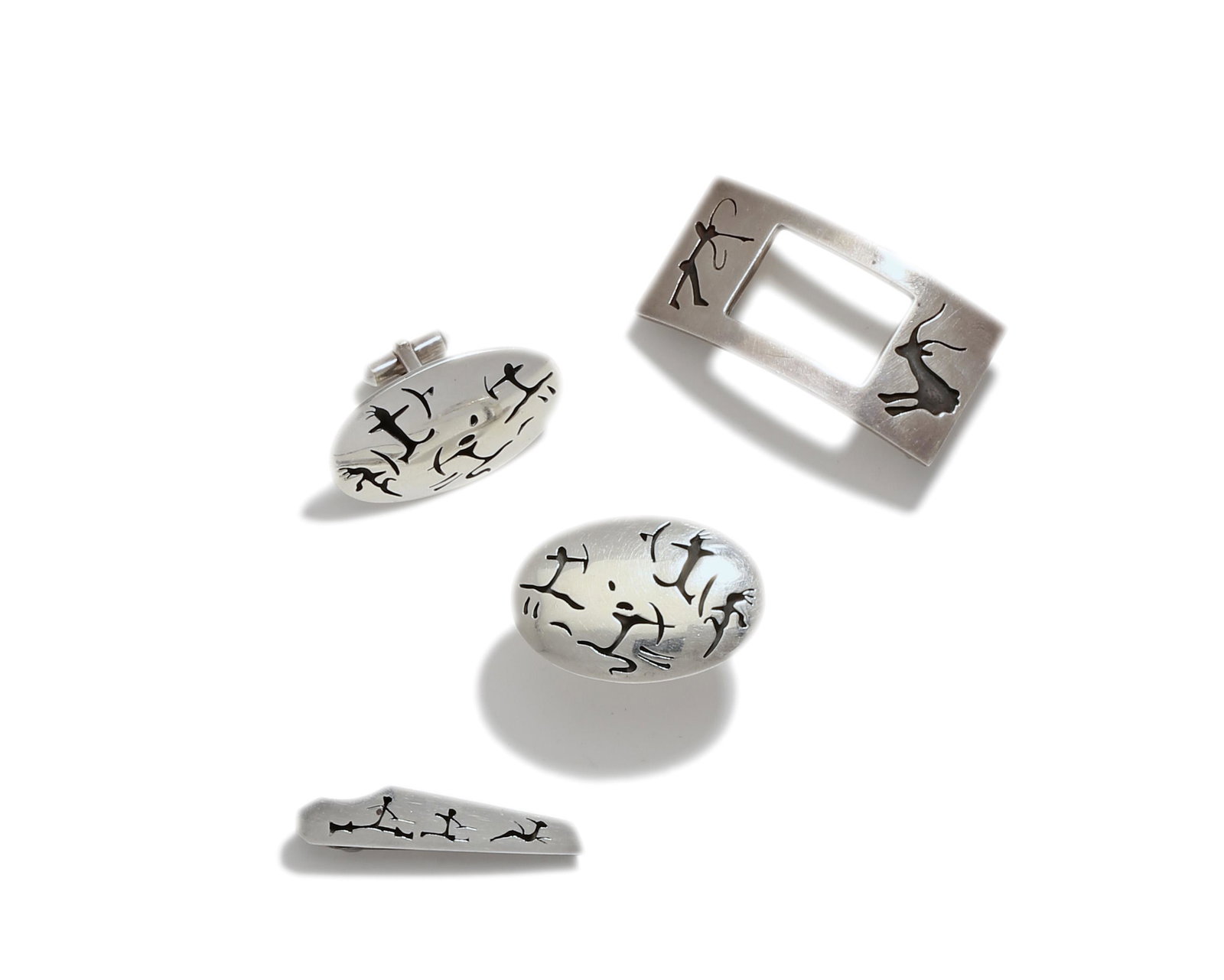A suite of Antonio Pineda Lascaux-motif jewelry: 1953-1979 Crown mark for Antonio Pineda; Eagle 17; Further stamped: Hecho en Mexico / Sterling Taxco 925 / Hilda / 970 Comprising a pair of silver cufflinks, belt buckle, and tie clip, 4 pieces Larges