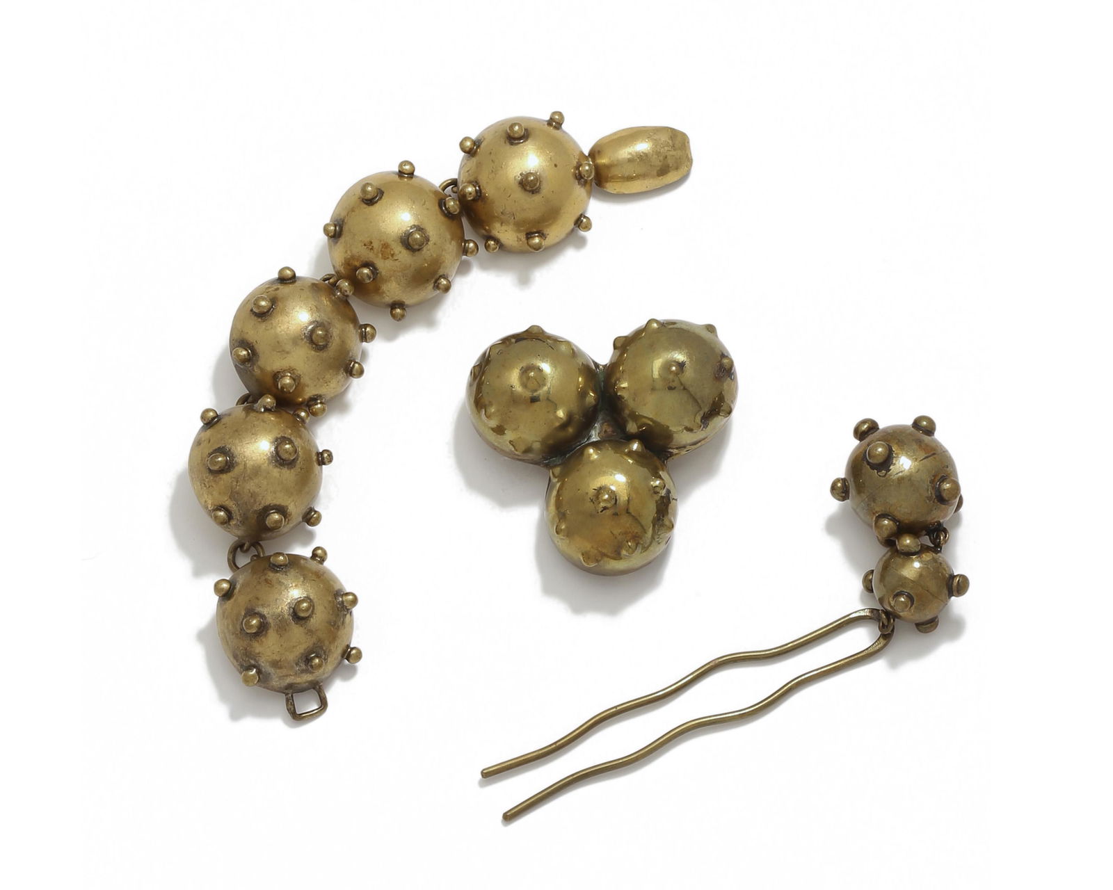 A set of Hubert Harmon bomb-motif jewelry items: Circa 1940s Each stamped: Hubert Harmon Mexico Comprising a hair ornament, a bracelet, and a pendant/brooch in a brass bomb-motif design, 3 pieces Largest: 1.125" H x 7" W Provenance: T