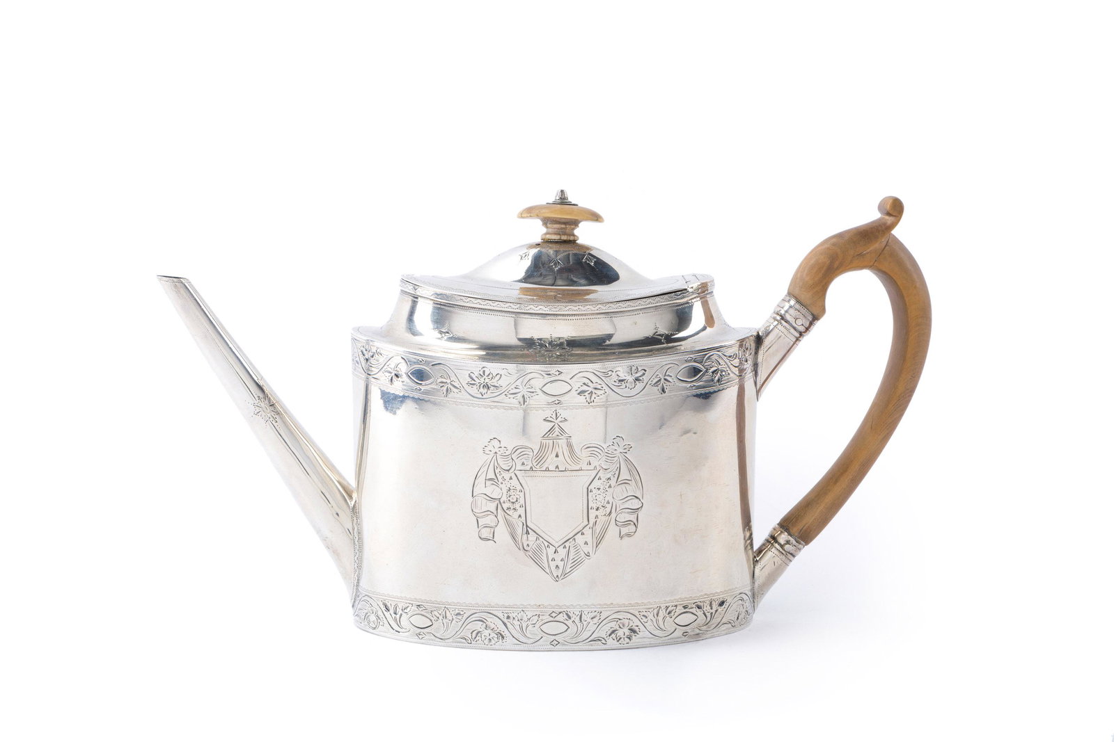 An English George III sterling silver teapot: 1791, London Stamped for Wildman Smith The bone finial over an oval engraved body centering a cartouche with sandalwood handle 6" H x 10.75" W x 3.875" D 14.400 oz. troy approximately