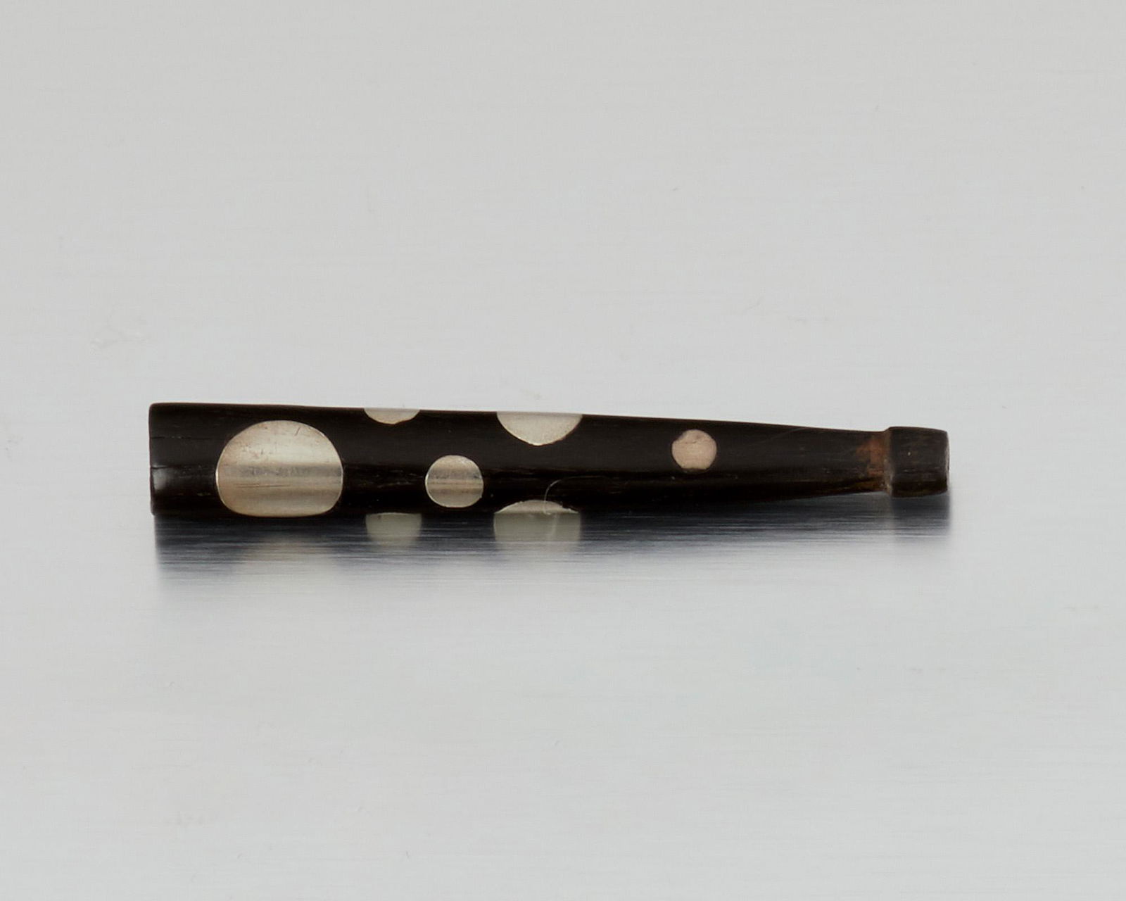 A William Spratling ebony and silver cigarette holder: 1949-1956; Second or Third Design Period; Taxco, Mexico Stamped for William Spratling Designed with nine discs of inlaid silver 3.5" H x .5" Dia. 8.5 grams Provenance: The Collection of Cindy Ti