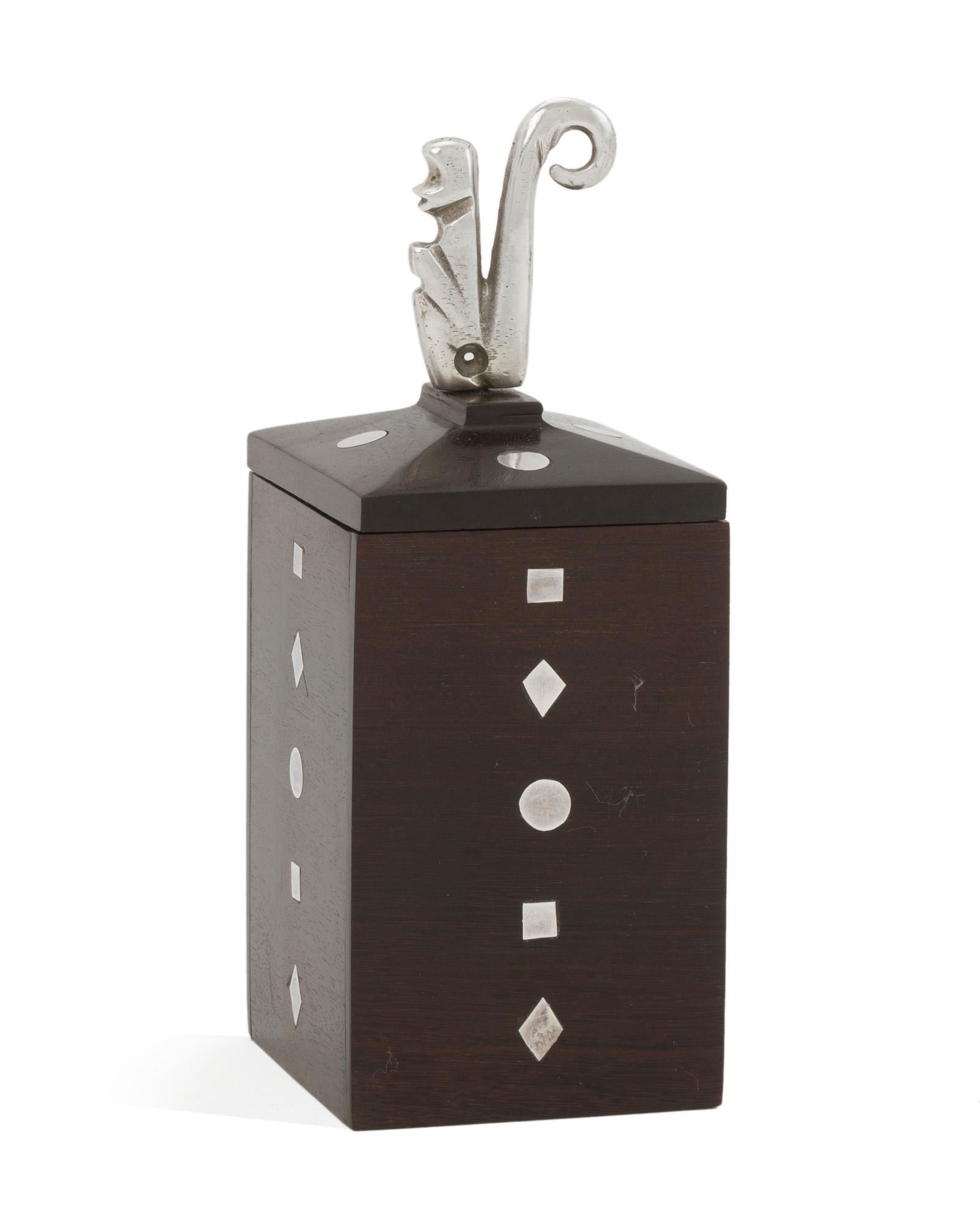 A William Spratling ebony and sterling silver box: 1964-1967; Third Design Period; Taxco, Mexico Stamped for William Spratling; Further stamped: 925 / Indistinct Eagle The ebony box topped with a stylized monkey finial and set with geometric inlaid