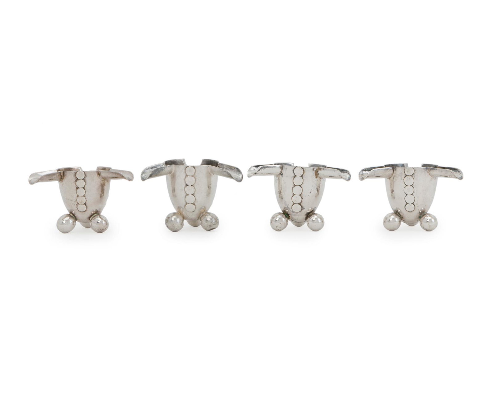 Four William Spratling silver ashtrays: 1940-1944; First Design Period; Taxco, Mexico Each stamped for William Spratling; Further stamped: Spratling Silver Each ashtray issuing three cigarette rests over a body with applied silver disks rai