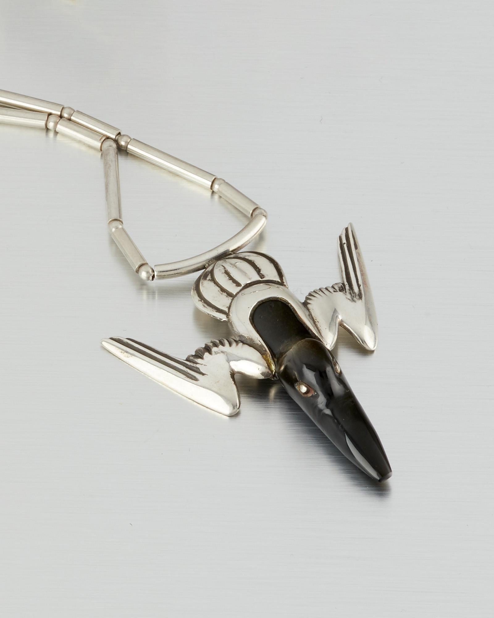 A William Spratling silver and obsidian hummingbird: 1949-1956; Third Design Period; Taxco, Mexico Stamped for William Spratling; Further stamped: Eagle 63 The stylized obsidian-set hummingbird pendant suspended from an attached tube-and-ball neckchai