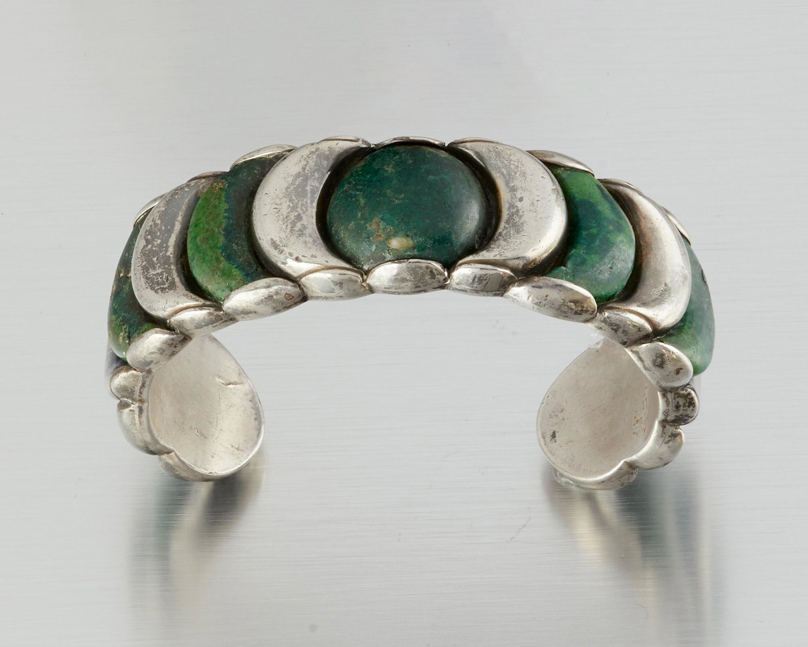 A William Spratling silver and hardstone cuff bracelet: 1940-1946; First Design Period; Taxco, Mexico Stamped for William Spratling; Further stamped Made in Mexico / Spratling Silver Designed with a crescent motif of alternating silver and green hardstone 