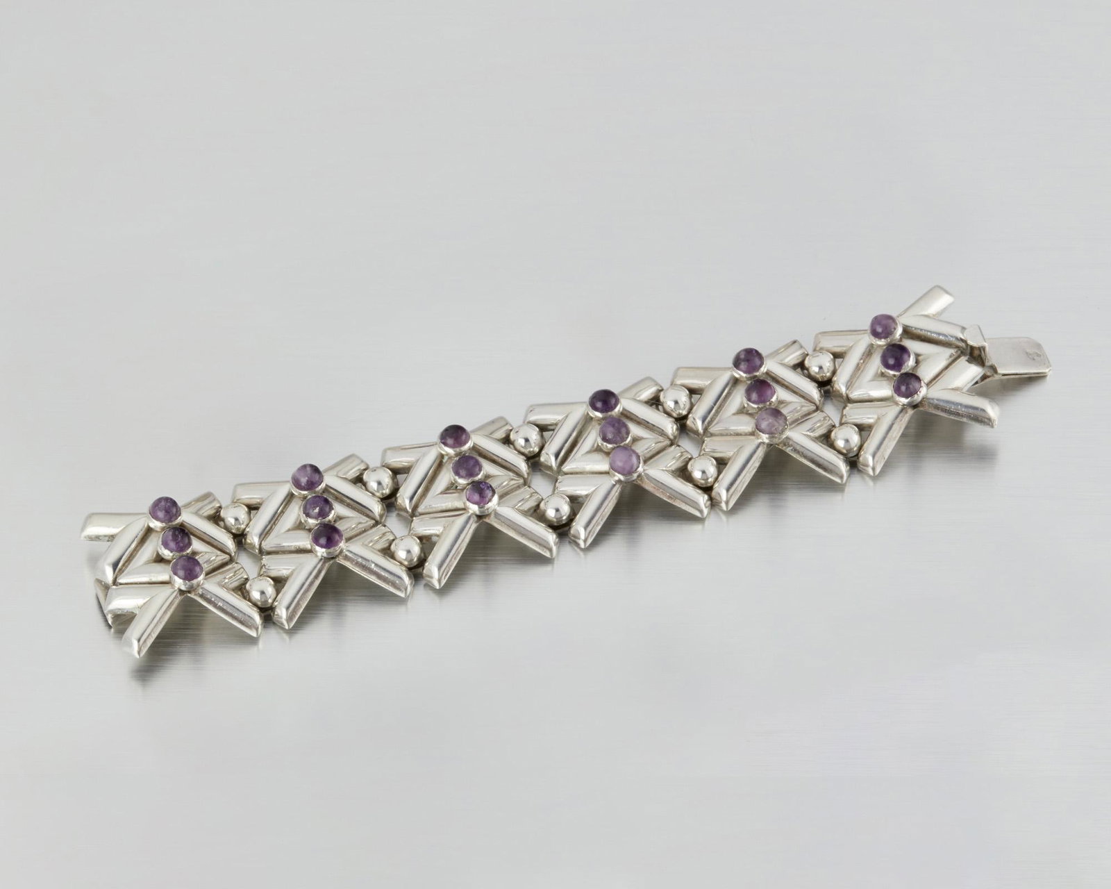 A Fred Davis silver and amethyst bracelet: Second quarter 20th century; Mexico City, Mexico Stamped: FD for Fred Davis; Further stamped: Silver / Mexico Designed as a stylized "X"-link with round amethyst cabochons 7" L x 1.25" H 77.0 grams Pr