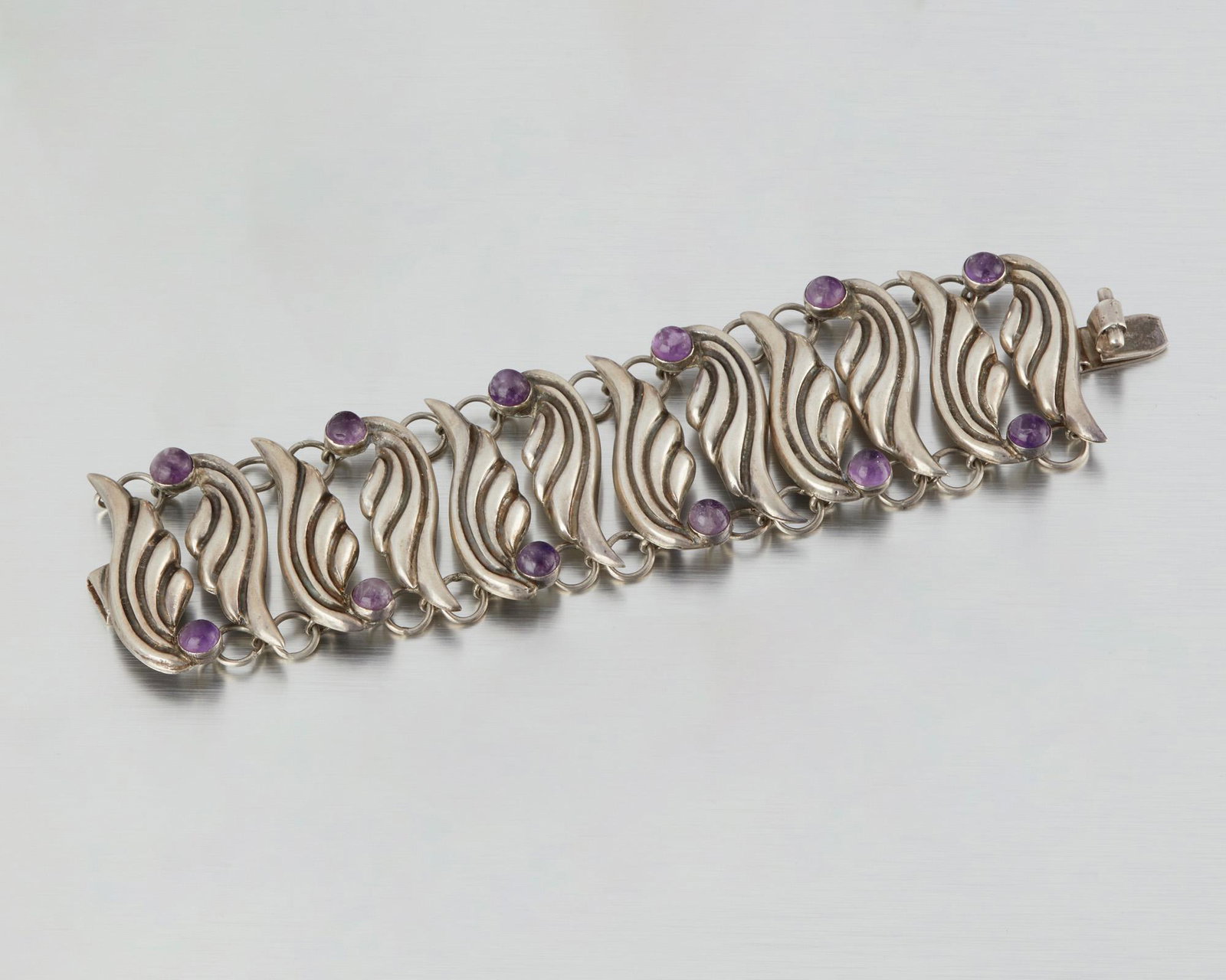 A Fred Davis silver and amethyst bracelet: Second quarter 20th century; Mexico City, Mexico Stamped: FD for Fred Davis; Further stamped: Made in Mexico / Silver Designed as a stylized wing-link bracelet tipped with amethyst cabochons 7.25" L x