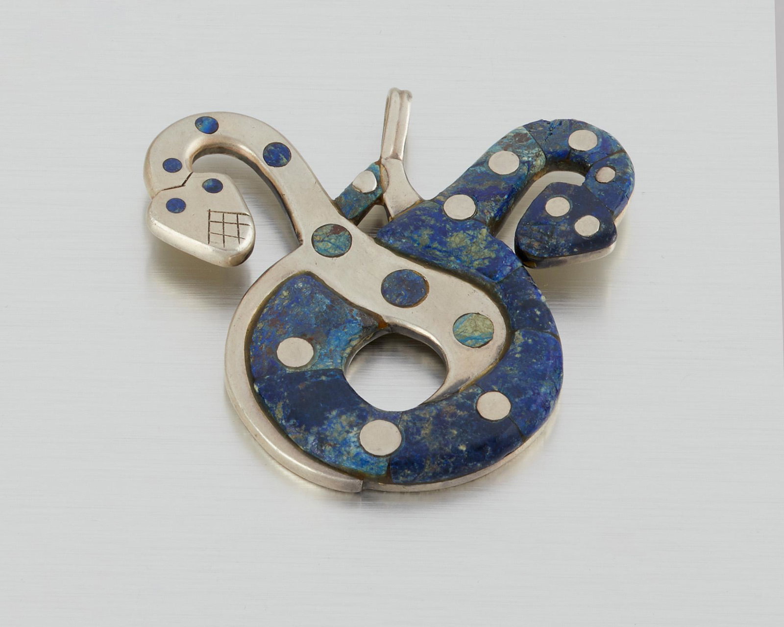 A William Spratling sterling silver and azurmalachite: 1951-1956; Third Design Period; Taxco, Mexico Stamped for William Spratling; Further stamped: 925 The two-headed serpent pendant set with carved azurmalachite 2.5" H x 2.5" W 82.5 grams Provenance: Th