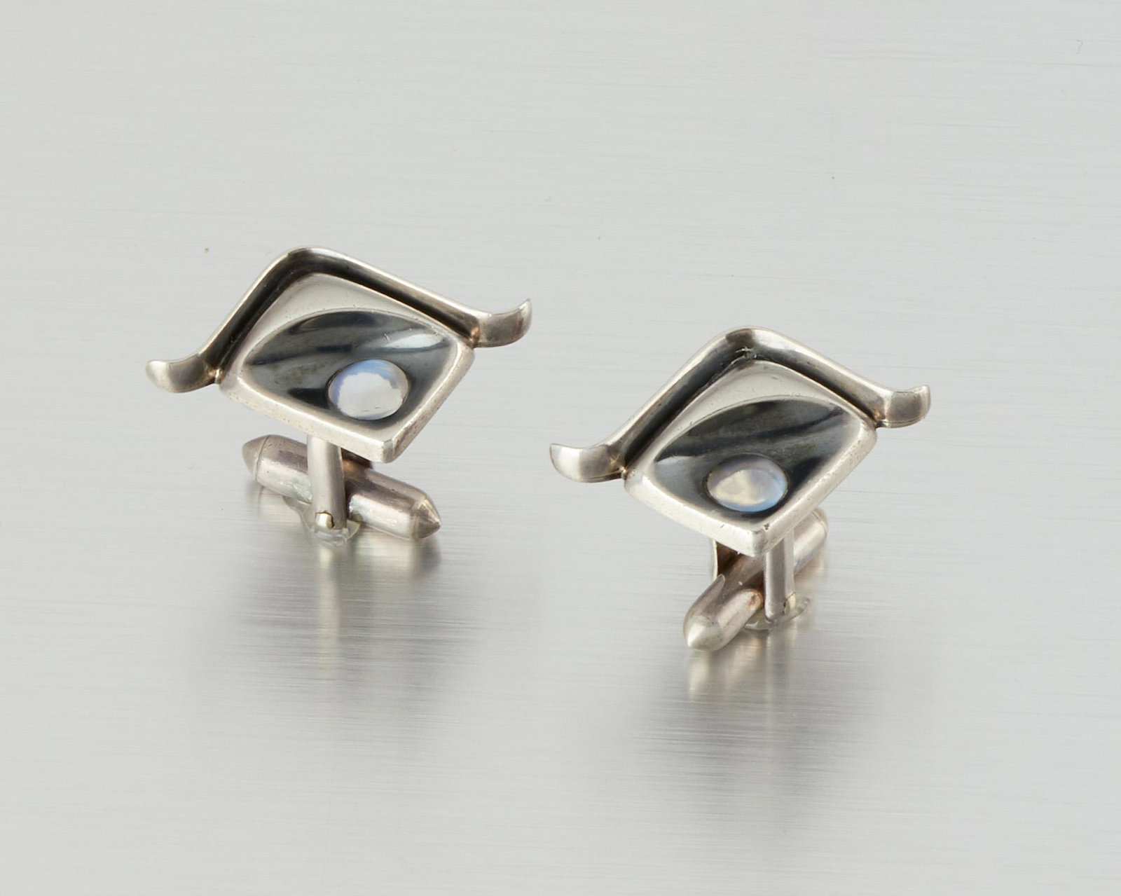 A pair of Antonio Pineda and Los Castillo silver and: 1962-1963; Taxco, Mexico Crown mark for Antonio Pineda; Eagle 58; Further stamped: 970 / Hecho en Mexico / Los Castillo Soc Coop Scl Sec 2 The asymmetrical square cufflinks set with moonstone cabochon