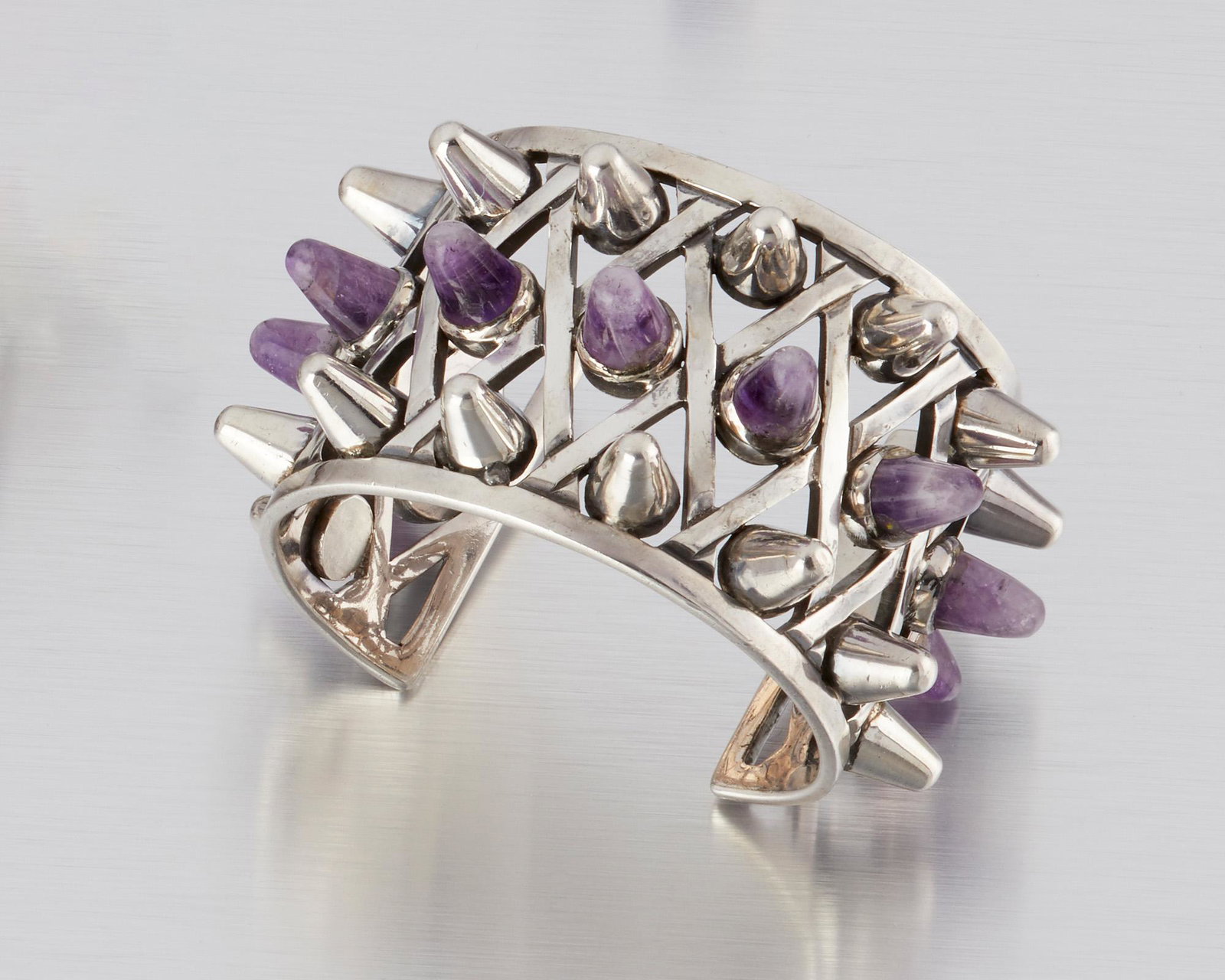 An Antonio Pineda silver and amethyst cuff bracelet: 1953-1979; Taxco, Mexico Crown mark for Antonio Pineda; Eagle 17; Further stamped: 970 The latticework-style cuff bracelet with silver and amethyst cones 7" C x 1.75" H with a 1.25" wrist opening 139.