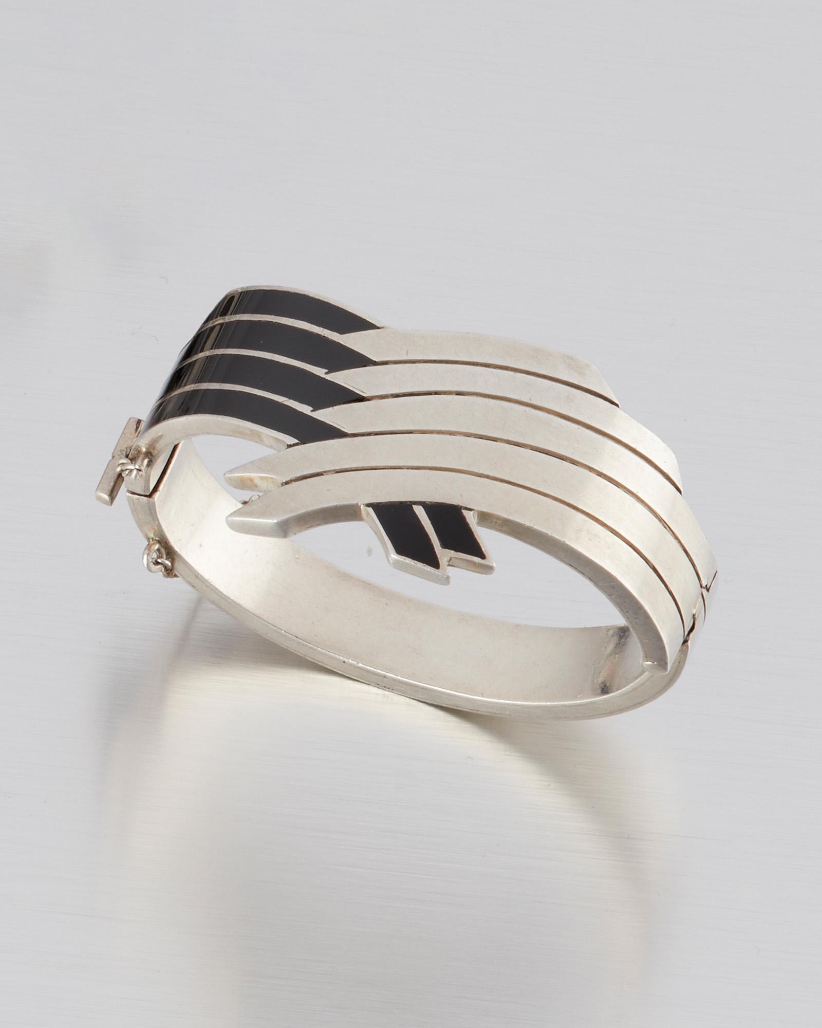 An Antonio Pineda silver and black enamel bracelet: 1953-1979; Taxco, Mexico Crown mark for Antonio Pineda; Eagle 17; Further stamped: Sterling / Mexico / Silver / 970 / ZZ854 The hinged bangle designed with interwoven bands of silver and black enamel 