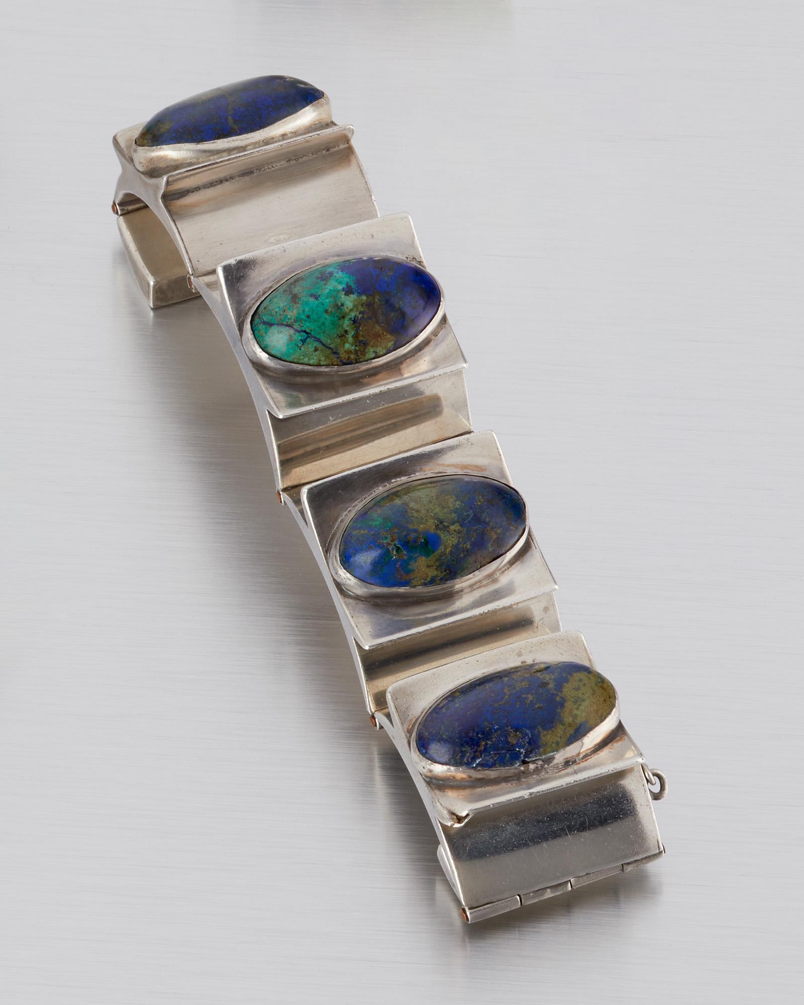 An Antonio Pineda silver and azurmalachite bracelet: 1941-1950; Taxco, Mexico Stamped AP for Antonio Pineda; Further stamped: Silver / Mexico / ZZ447 Designed with concave and convex links featuring oval azurmalachite cabochons 6.5" L x 1.125" H 137.5 g