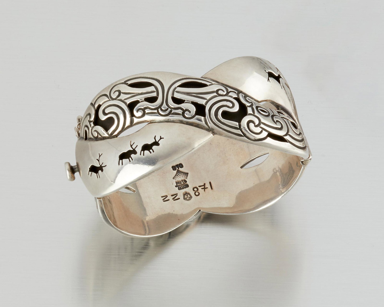An Antonio Pineda Lascaux-motif silver bracelet: 1953-1959; Taxco, Mexico Crown mark for Antonio Pineda; Eagle 3; Further stamped: 970 / Mota Taxco / ZZ871 The hinged bangle bracelet designed with crossover Lascaux and Pre-Columbian motif bands 7" C