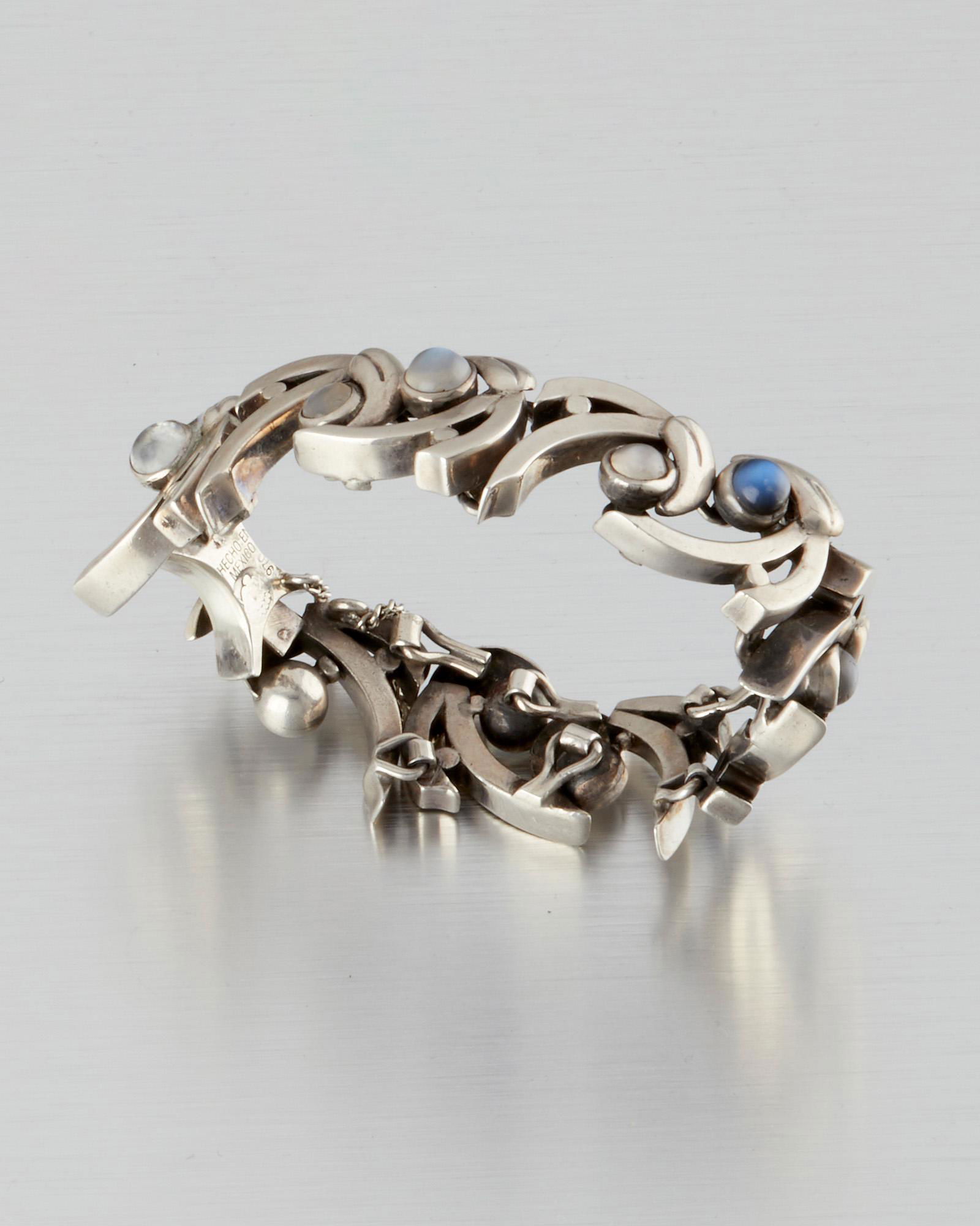 An Antonio Pineda silver and moonstone bracelet: 1953-1979; Taxco, Mexico Crown mark for Antonio Pineda; Eagle 17; Hecho en Mexico / 970 Designed with a stylized "A"-motif with round blue and white moonstone cabochons 6.5" L x .875" H 85.0 grams