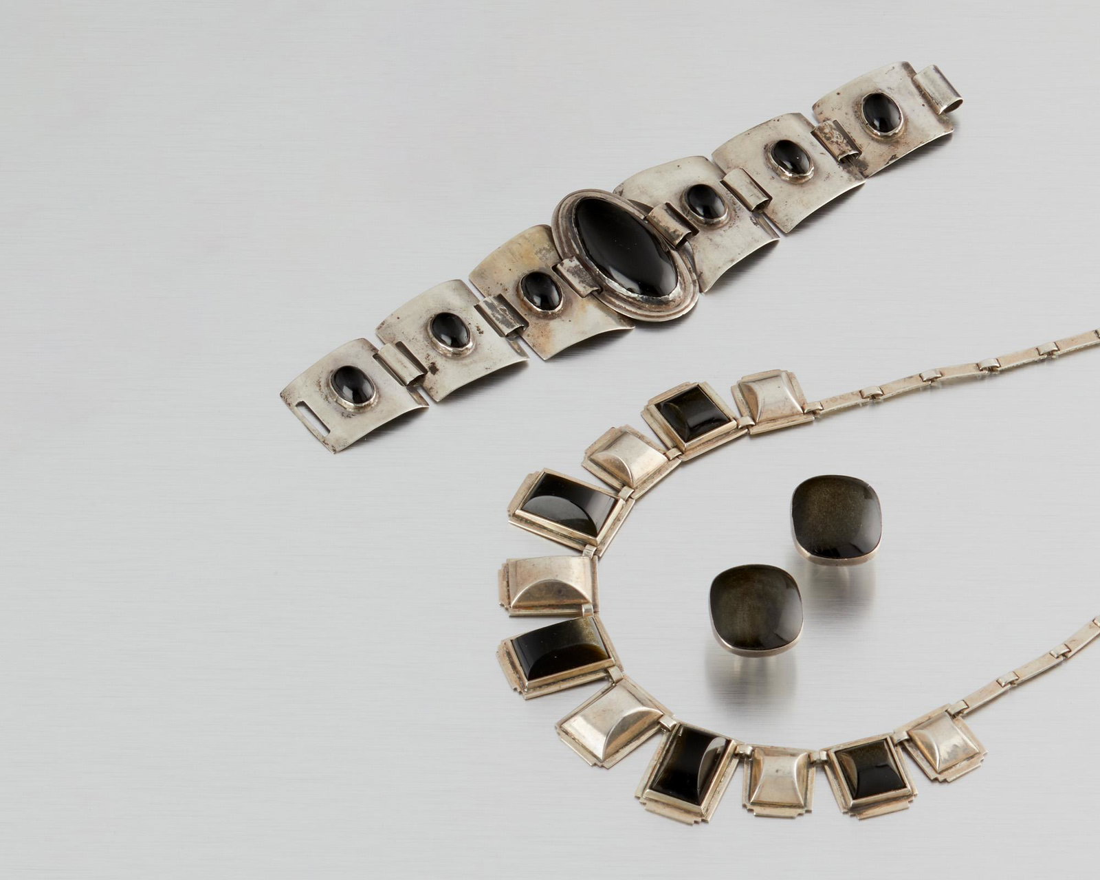 An assembled suite of Fred Davis silver and obsidian: Second quarter 20th century; Mexico City, Mexico Stamped: FD for Fred Davis: Earrings further stamped: Made in Mexico Comprising a necklace designed with alternating links of obsidian and silver arc