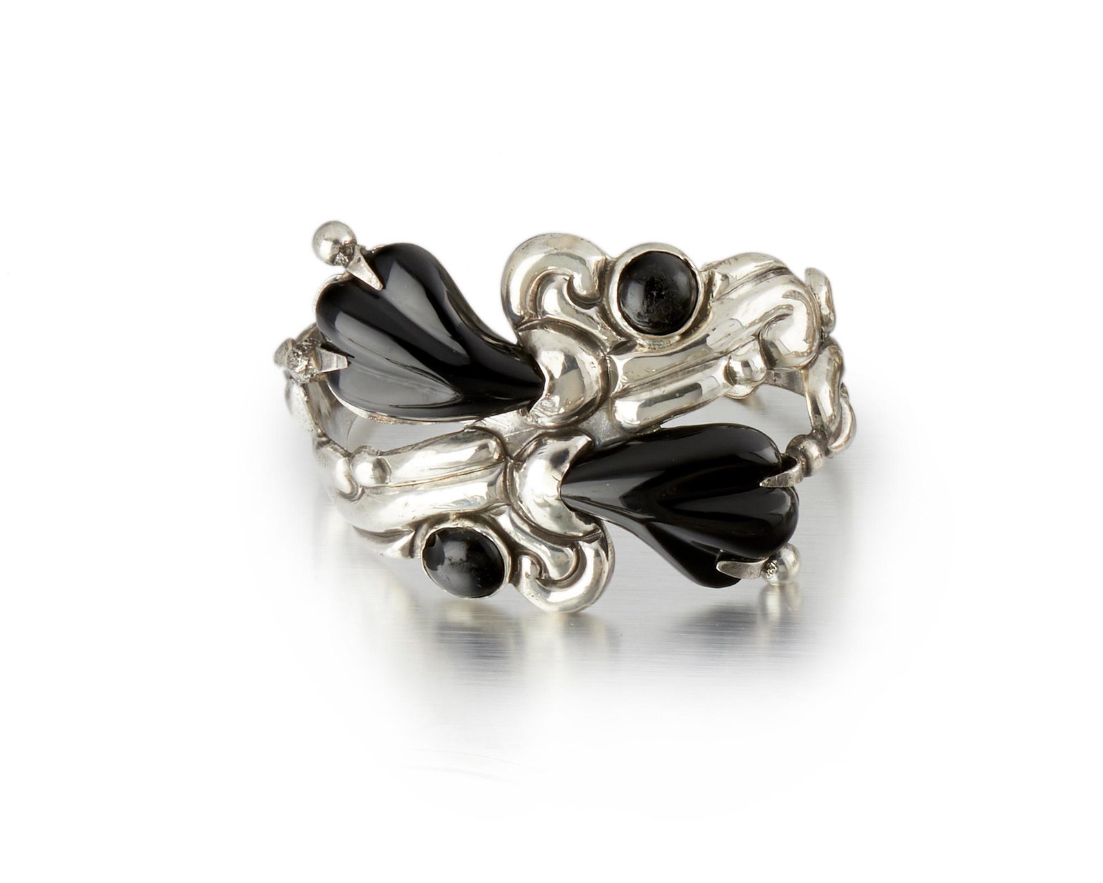 A Hector Aguilar silver and black stone cuff bracelet: 1943-1948; Taxco, Mexico Stamped for Hector Aguilar; Further stamped: Made in Mexico / Sterling Designed as a stylized carved onyx and obsidian flower cuff bracelet 6.5" C x 2" H with a 1.25" wrist