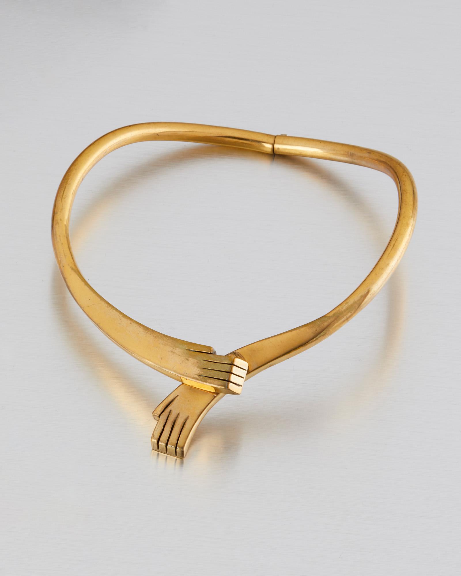 A Los Castillo brass necklace: Third quarter 20th century; Taxco, Mexico Stamped: Mexico / Los Castillo The rigid collar necklace in the form of two draped hands 14" C x 1.625" H Provenance: The Collection of Cindy Tietze-Hodosh an