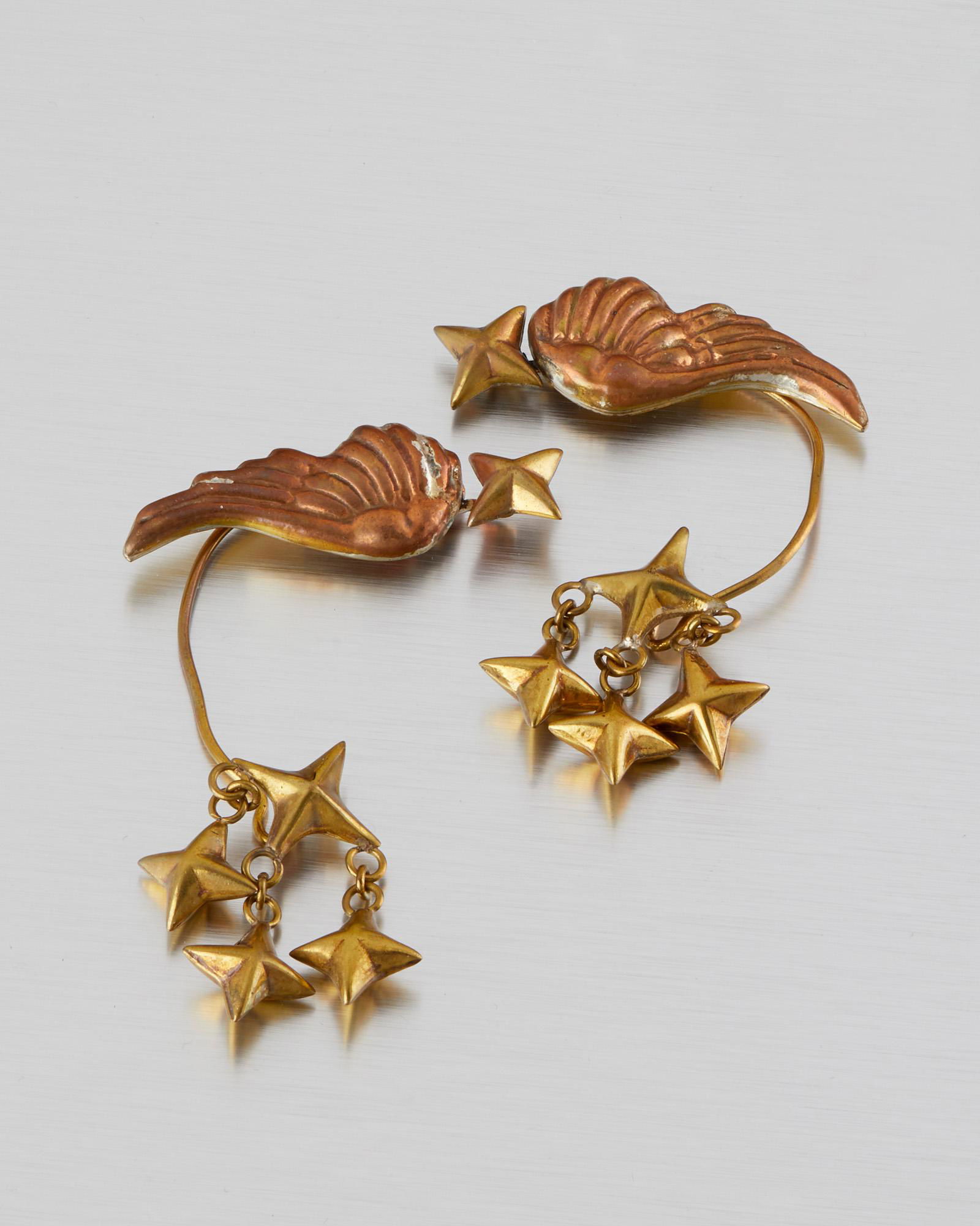 A pair of Hubert Harmon mixed-metal ear cuffs: 1942-1948; Taxco, Mexico Stamped with winged feet for Hubert Harmon Designed as repousse copper wings with a brass star motif, 2 pieces 4.625" H x 2.5" W 45.5 grams Provenance: The Collection of