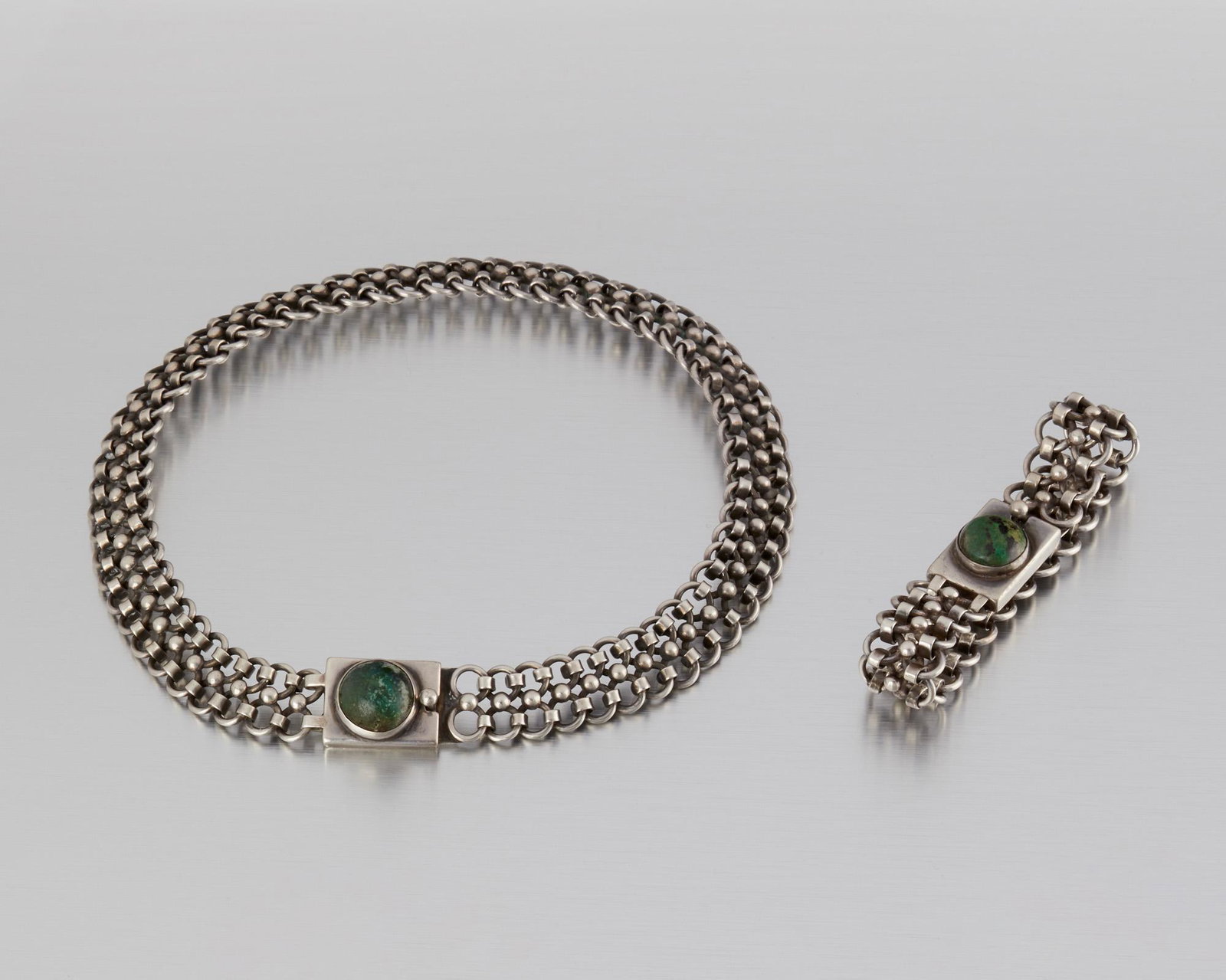 A set of Hector Aguilar silver and hardstone jewelry: 1943-1948; Taxco, Mexico Stamped for Hector Aguilar; Further stamped: Made in Mexico / Sterling Designed as a heavy double-link chain with a green hardstone-set clasp with a matching bracelet, 2 piece