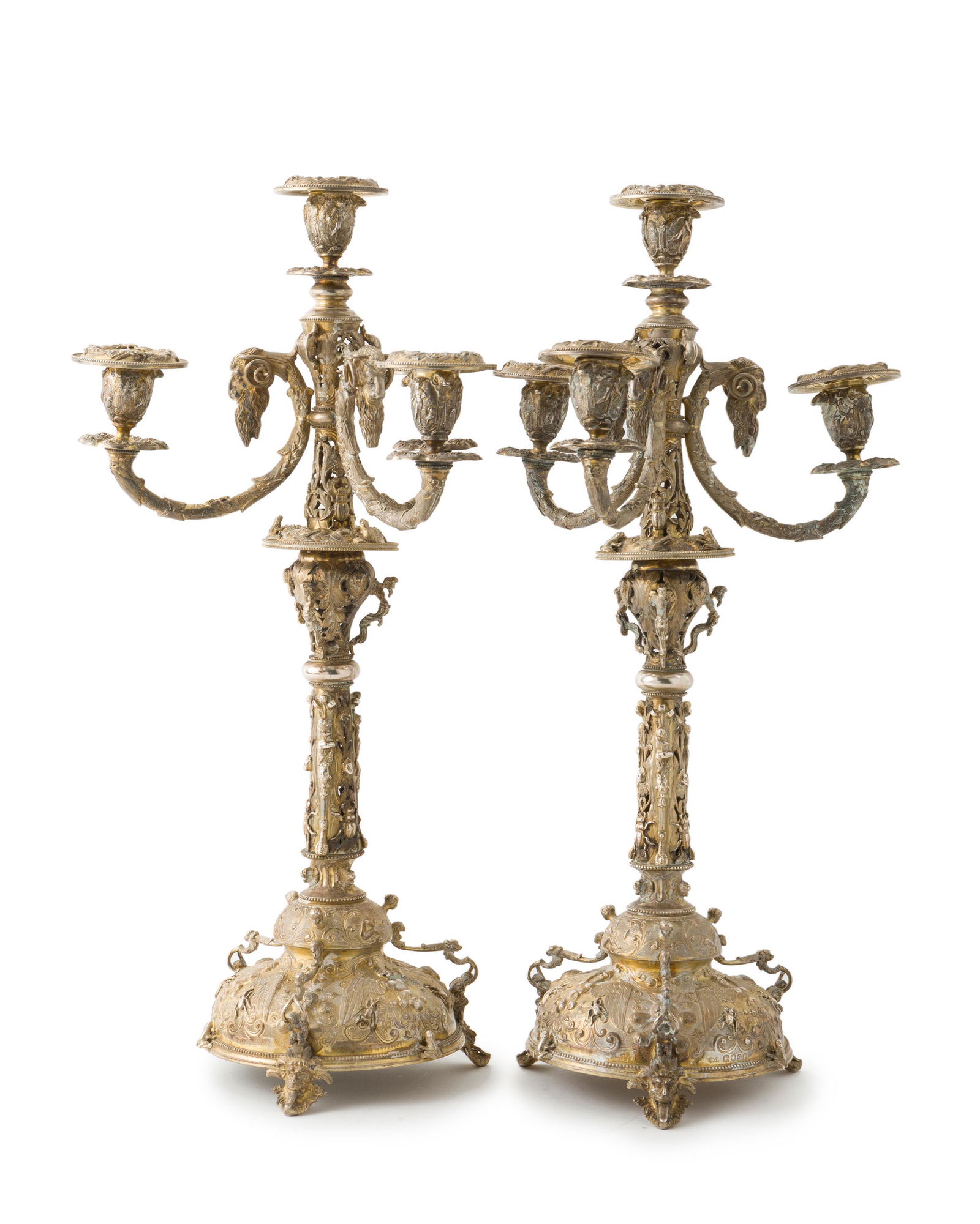 A pair of English sterling silver gilt-washed: 1873, London Stamped: AM for Alexander MacRae Each four-light candelabra with repousse neo-classical bobeches issuing from ram's head supports over an openwork standard decorated with beetles, frogs