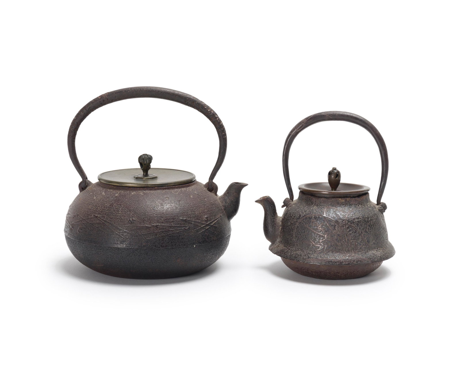 Two Japanese Tetsubin iron teakettles: Late 19th/early 20th century; Meiji period Smaller signed: Kinshudo, in incised characters below handle on back; Larger stamped twice below spout for Shokodo Larger with: Geometric pattern and lid wit