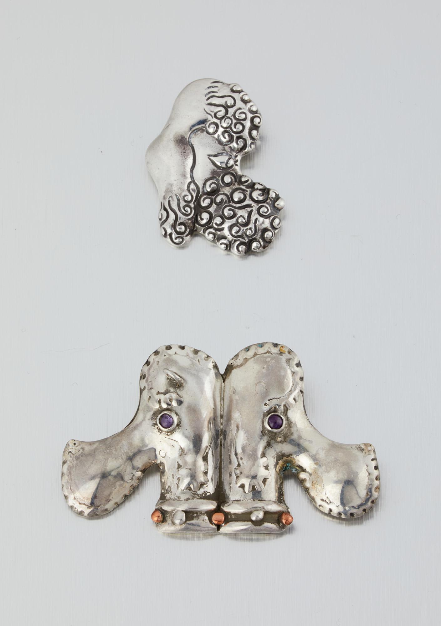 Two Hubert Harmon silver poodle brooches: Circa 1940s; Taxco, Mexico Each stamped for Hubert Harmon Comprising a mixed-metal double-poodle head pendant/brooch with amethyst eyes (1.75" H x 3" W); And a single poodle head brooch (1.625" H x
