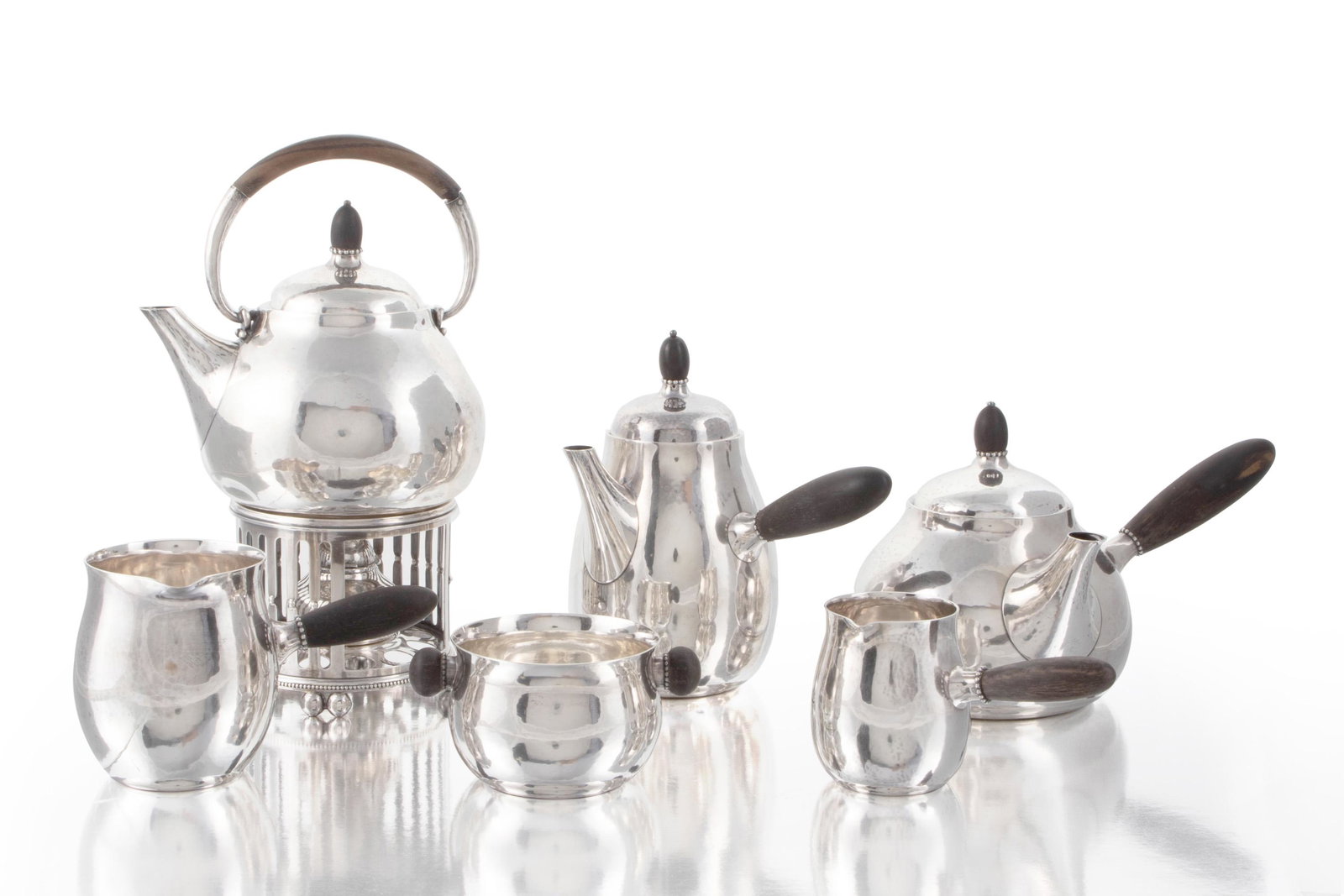 A Georg Jensen No. 80 tea and coffee service: 1925-1930 Each stamped: Georg Jensen / Denmark / Sterling / 80; Some further stamped and lettered Designed 1915 by Georg Jensen, comprising a tipping kettle, a coffee pot, a tea pot, a cream jug, a la