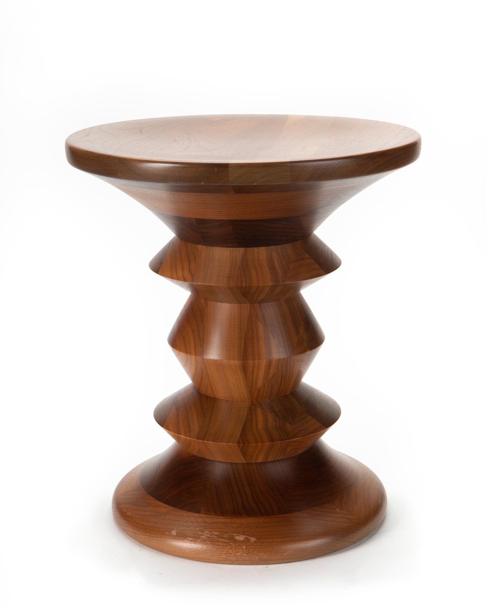 An Eames for Herman Miller turned wood stool: Second-half 20th Century The walnut stool/side table with concave top and bottom based on the original 1959 Eames designs for the Time-Life lobby at Rockefeller Center 15" H x 13.25" Dia.