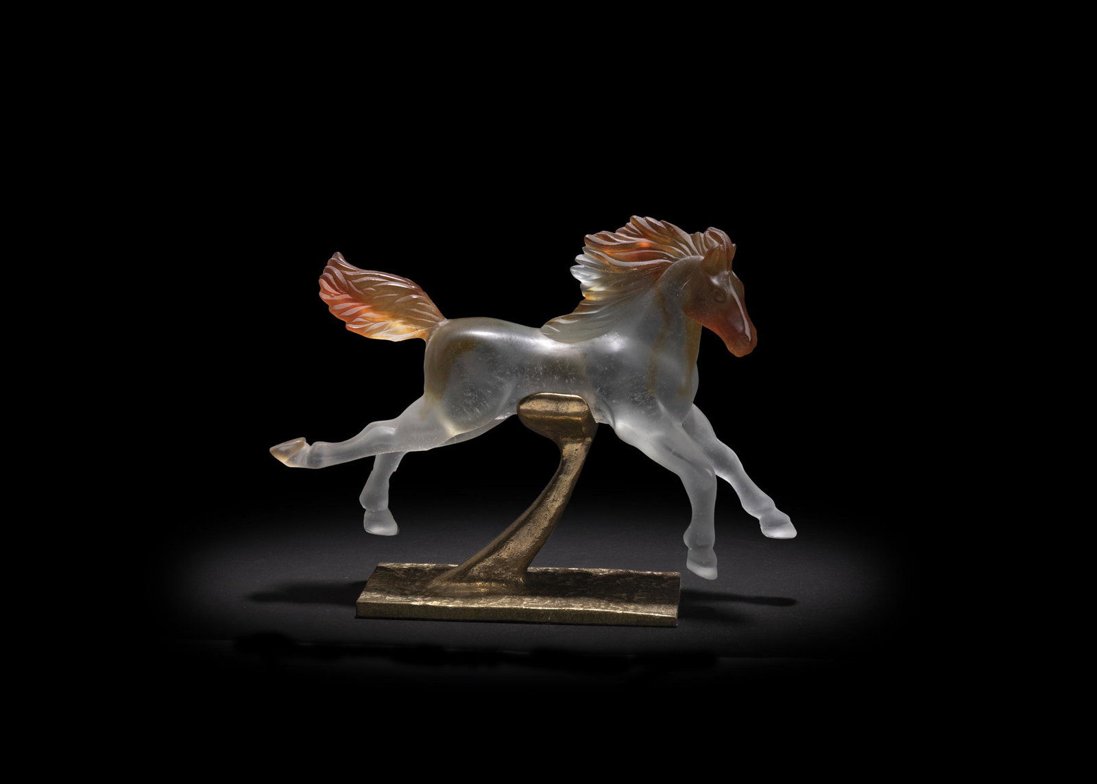A Daum pate de verre horse: Second-half 20th Century Apparently unmarked The clear and orange glass horse on a gilt-bronze pedestal Overall: 7.75" H x 10.5" W x 2.75" D Provenance: Property from a Northern Californian Estate