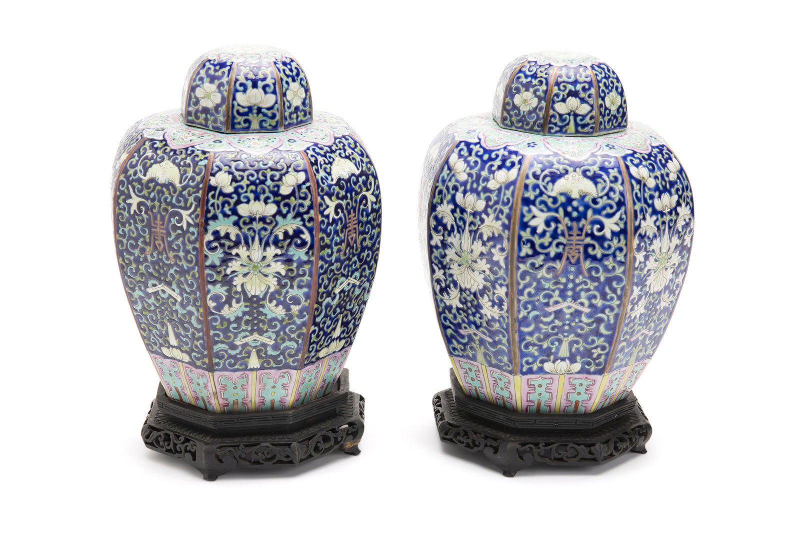 A pair of Chinese lidded ginger jars on wood stands: Mid-20th Century Each marked to base The octagonal formed jars and lids in dark blue, turquoise, and pink with floral design on a fitted black-painted wood stand, 2 pieces Each overall: 10.5" H x 6.75