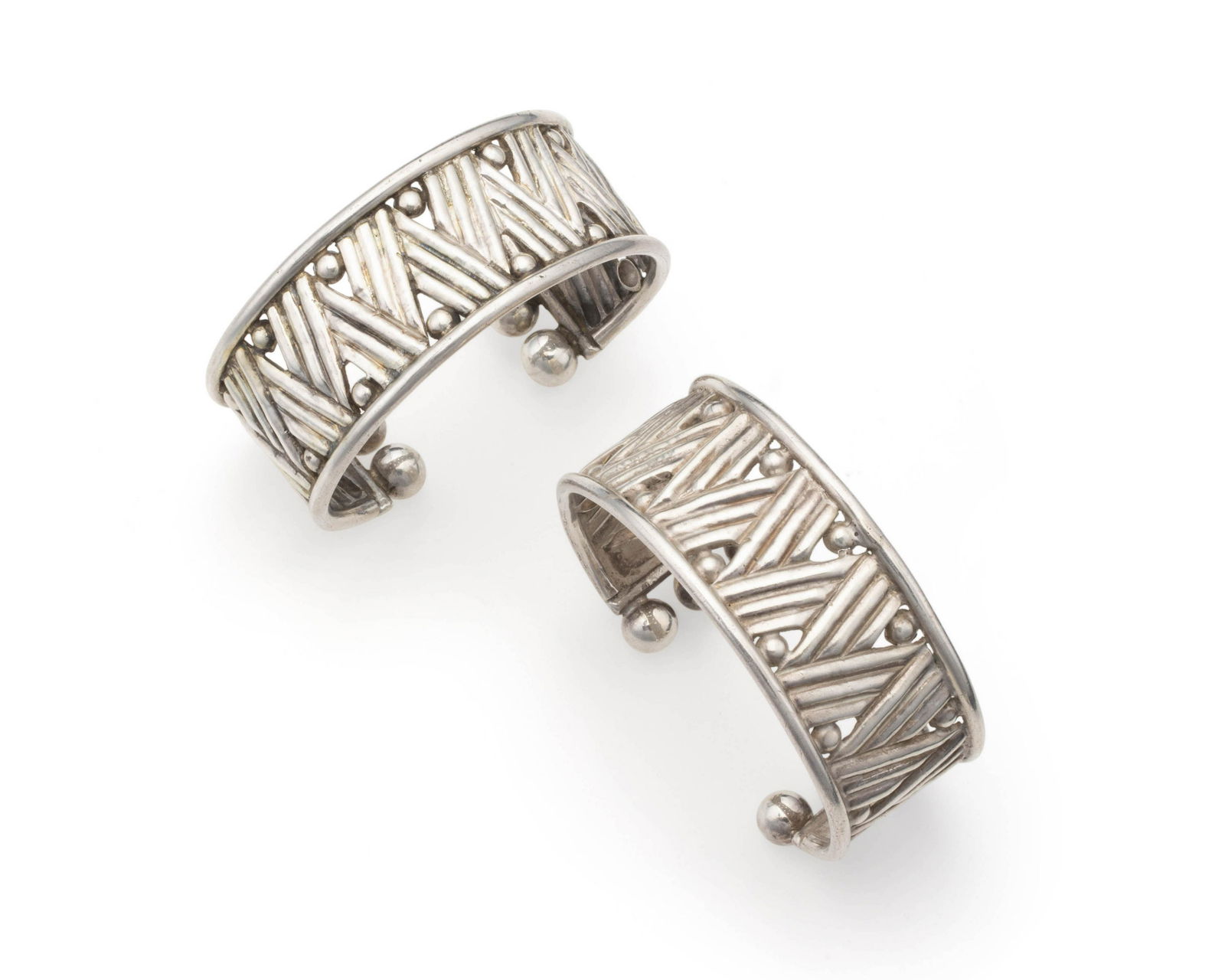 A pair of William Spratling silver cuff bracelets: Both 1940-1944; First Design Period; Taxco, Mexico Stamped for William Spratling; Further stamped: Made in Mexico / Silver Each designed with a linear zig-zag motif terminating with six silver spher
