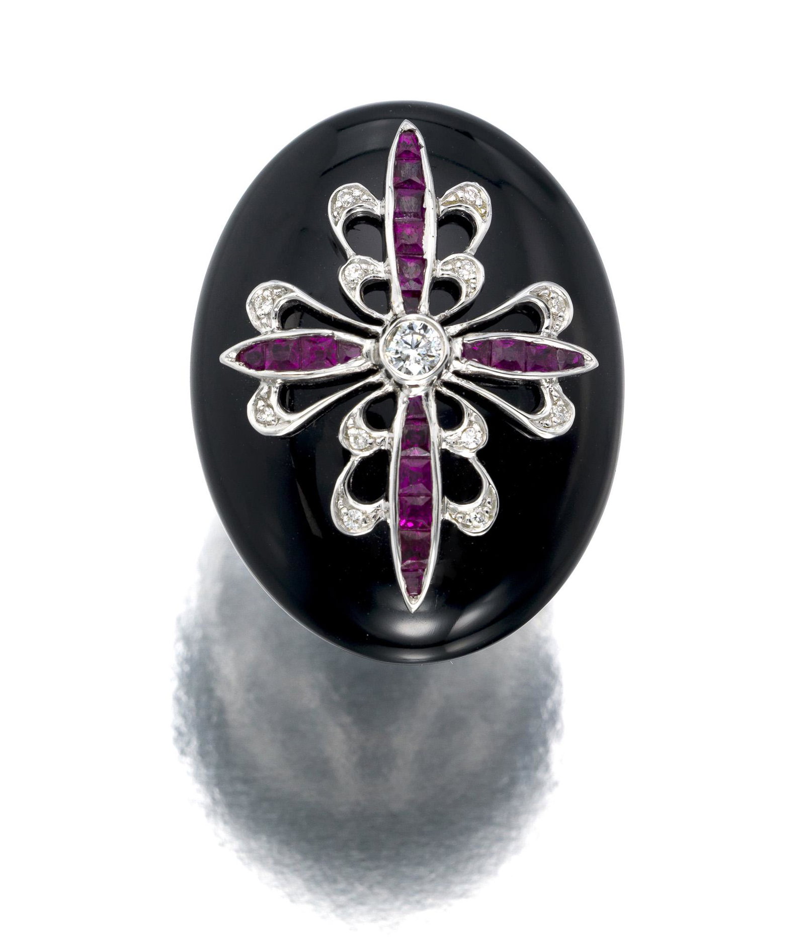 An onyx, ruby and diamond ring: 18k white gold The oval onyx cabochon set with twenty four calibre-cut rubies, further set with one old mine and twelve single-cut round diamonds totaling approximately 0.15 ct. and graded H-K color, 