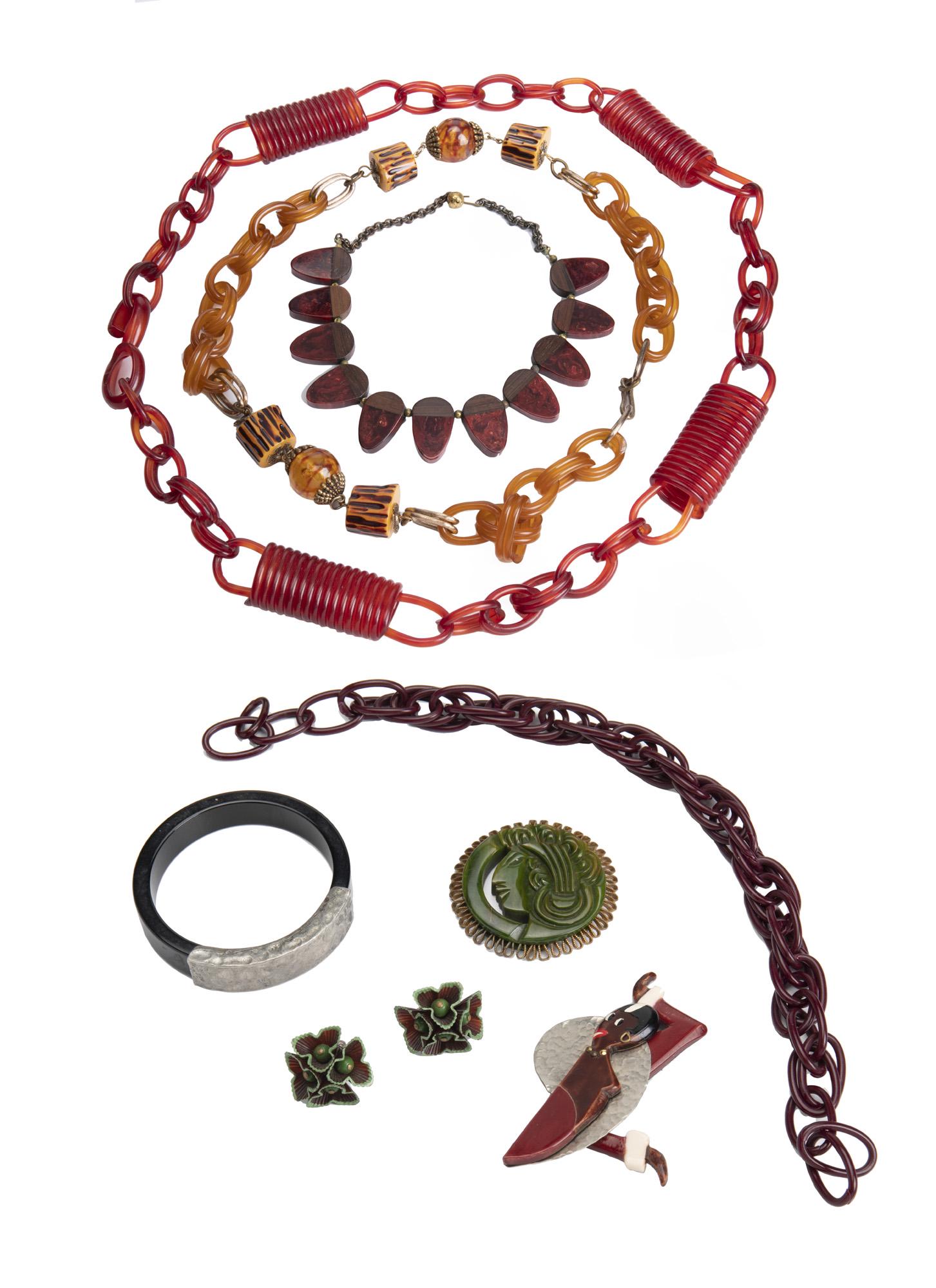 A group of Bakelite and plastic jewelry: Comprising four necklaces, two brooches (one possibly depicting Josephine Baker), a pair of ear clips, and one bangle bracelet Longest necklace: 35" L; Largest brooch: 3 1/8" H x 3" W 9 pieces