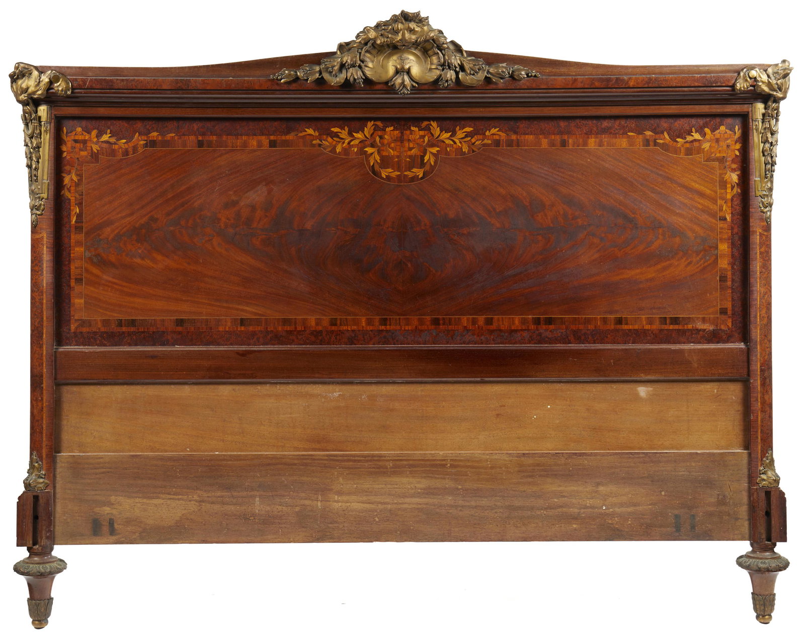 A French Louis XVI-style headboard: Late-19th Century The wood body with marquetry inlay and gilt bronze shell and lion-shaped mounts 48.5" H x 62" W x 5" D