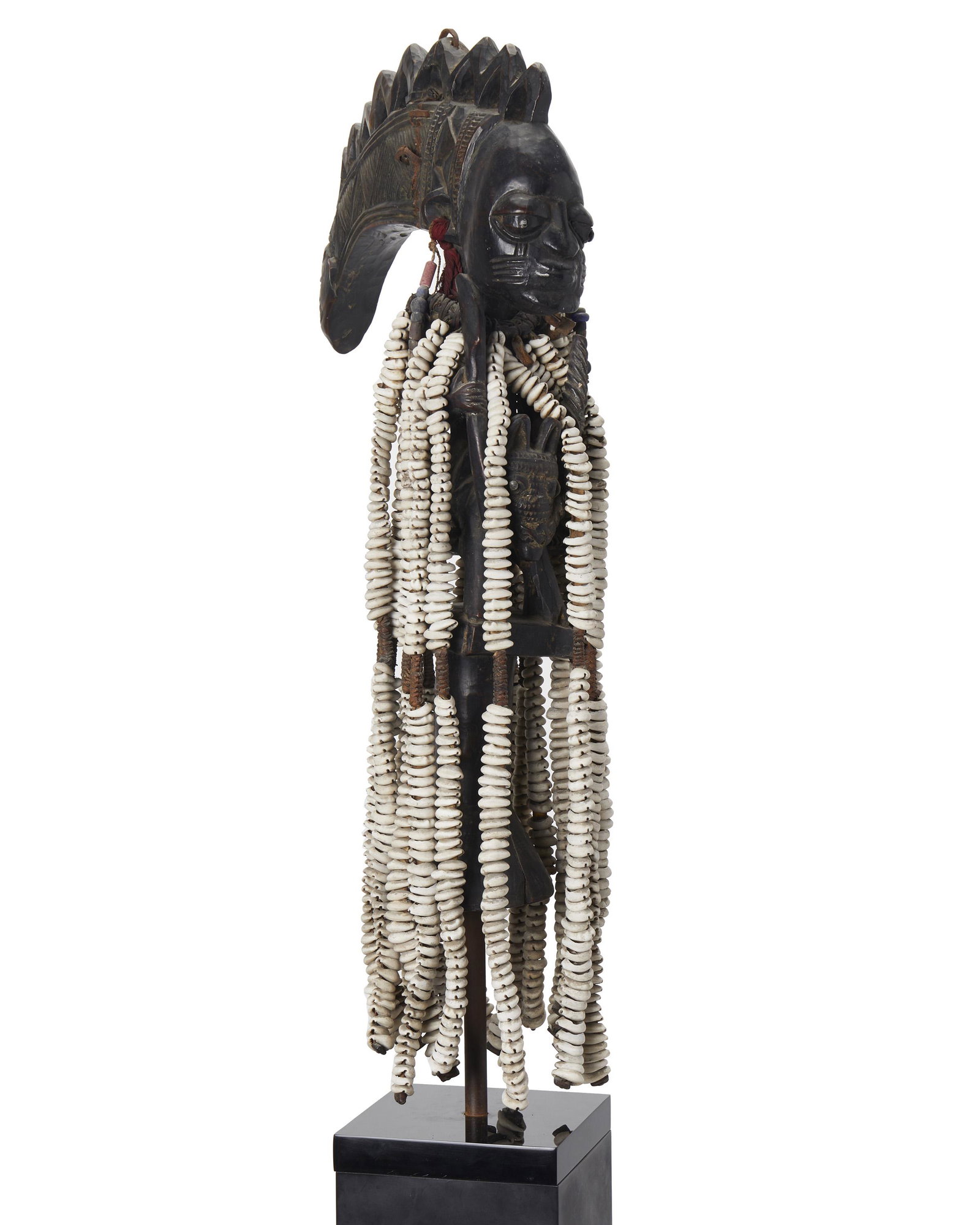 An African Eshu equestrian staff: Circa 1940-1950; Yoruba people, Nigeria The Yoruban Janus-faced figure astride a horse on a short staff with tribal scar markings, cloth and bead earrings, an extended headress crudely attached with i