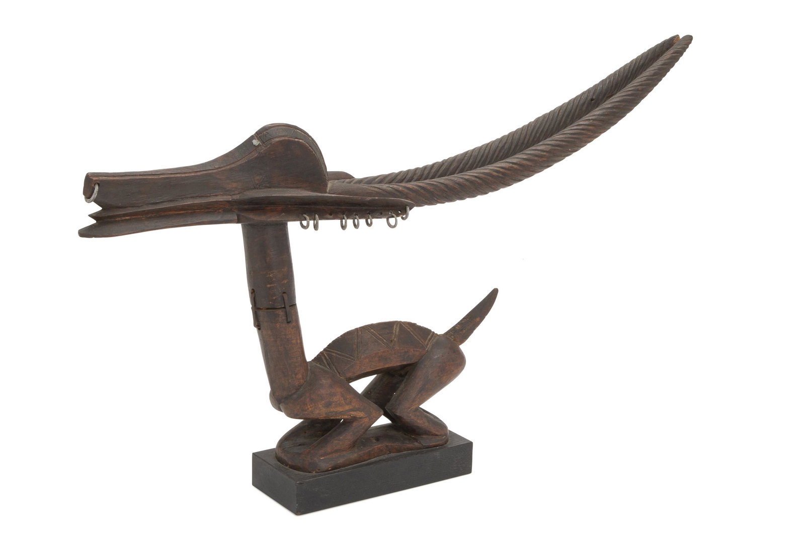 An African Chi Wara headdress: Bambara culture, Mali The stylized carved wood figure of a female antelope with pierced ears and small ring earrings comprised of two pieces of wood joined with iron staples 16.5" H x 5" W x 27.5" D P
