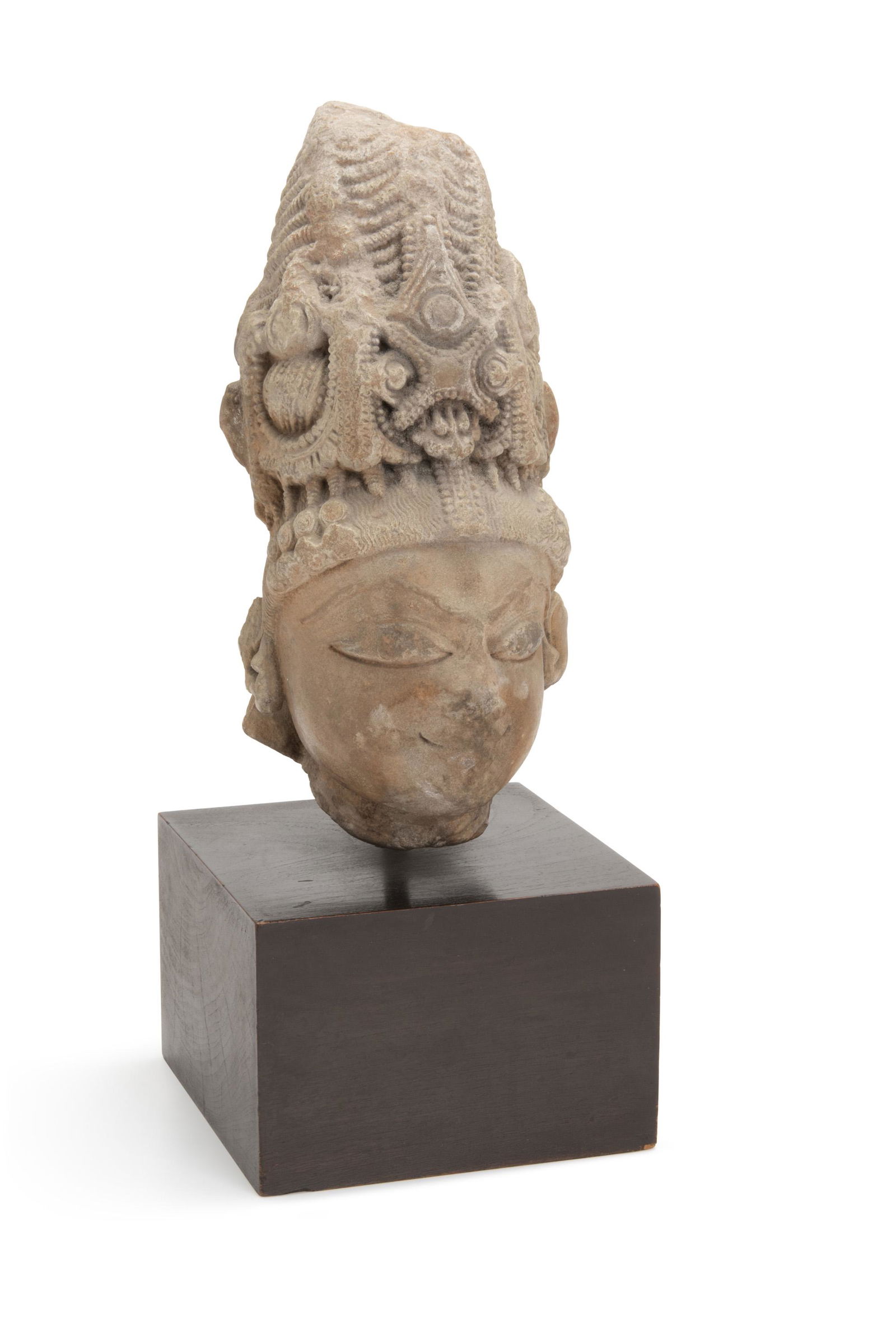 An Indian carved stone head of Vishnu: 5th Century, India The stone head with intricate headdress mounted on a black base 14.75" H x 6" W x 6" D Provenance: Collection of John Scott Acquired from the above by the present owner