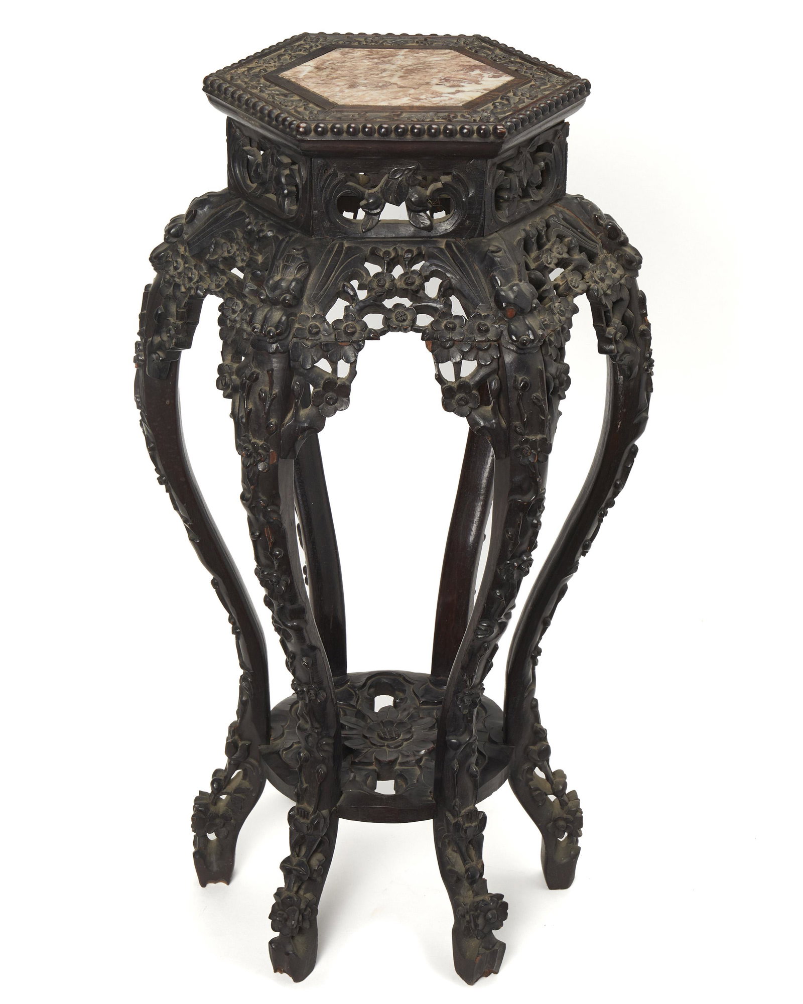A Chinese carved wood stand: Late-19th/early-20th Century Carved hardwood with inset marble top a over a tall and slender stand with carved dragon heads on the shoulder and flori-form undershelf 32.5" H x 18" Dia.