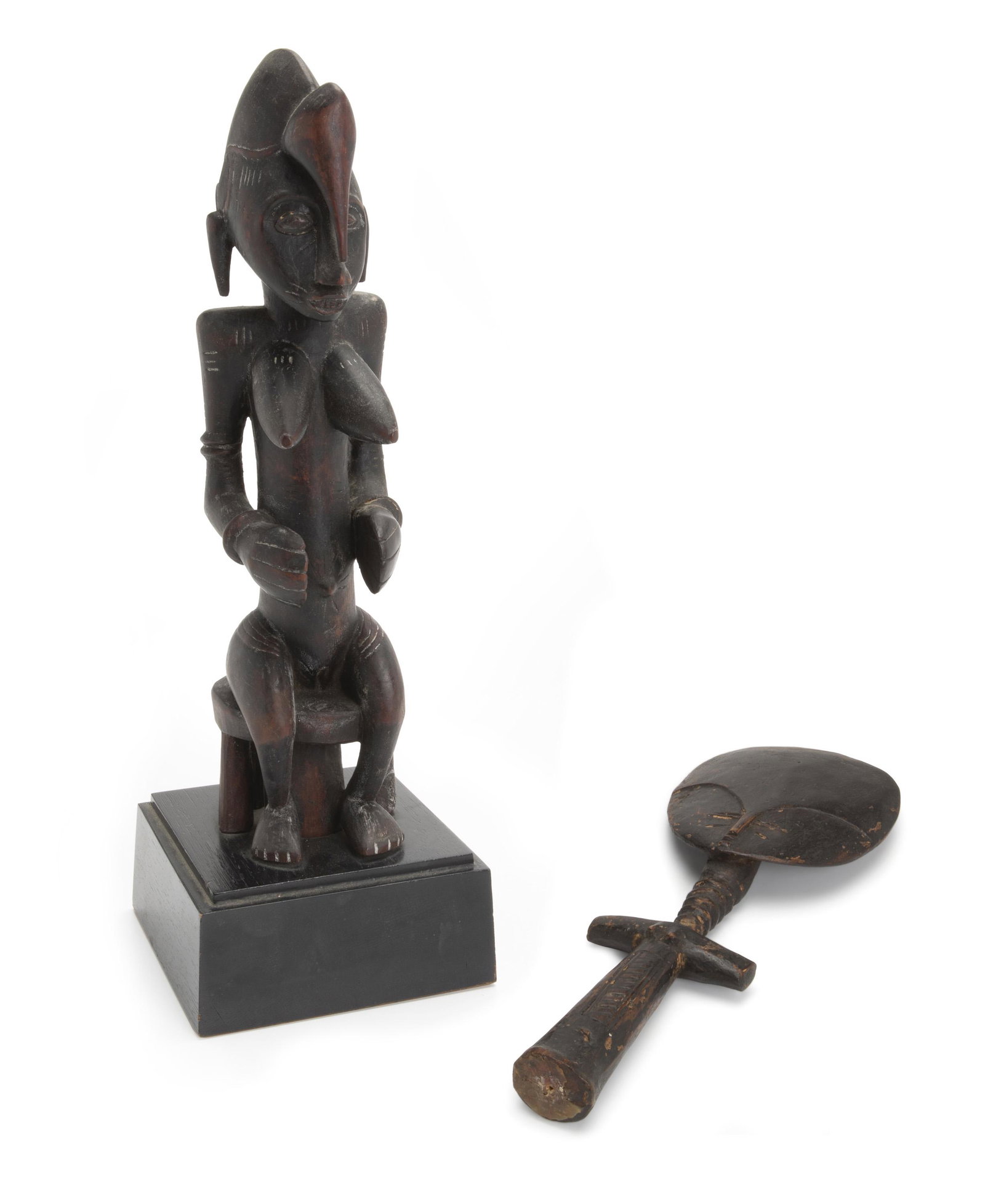 Two African carved female figures: 19th/20th Century Comprising a Ghanan Akuaba wooden fertility fetish doll with large flat disk-shaped head, stylized face, rudimentary arms, and tribal scar marks typical of the central Akan area toge