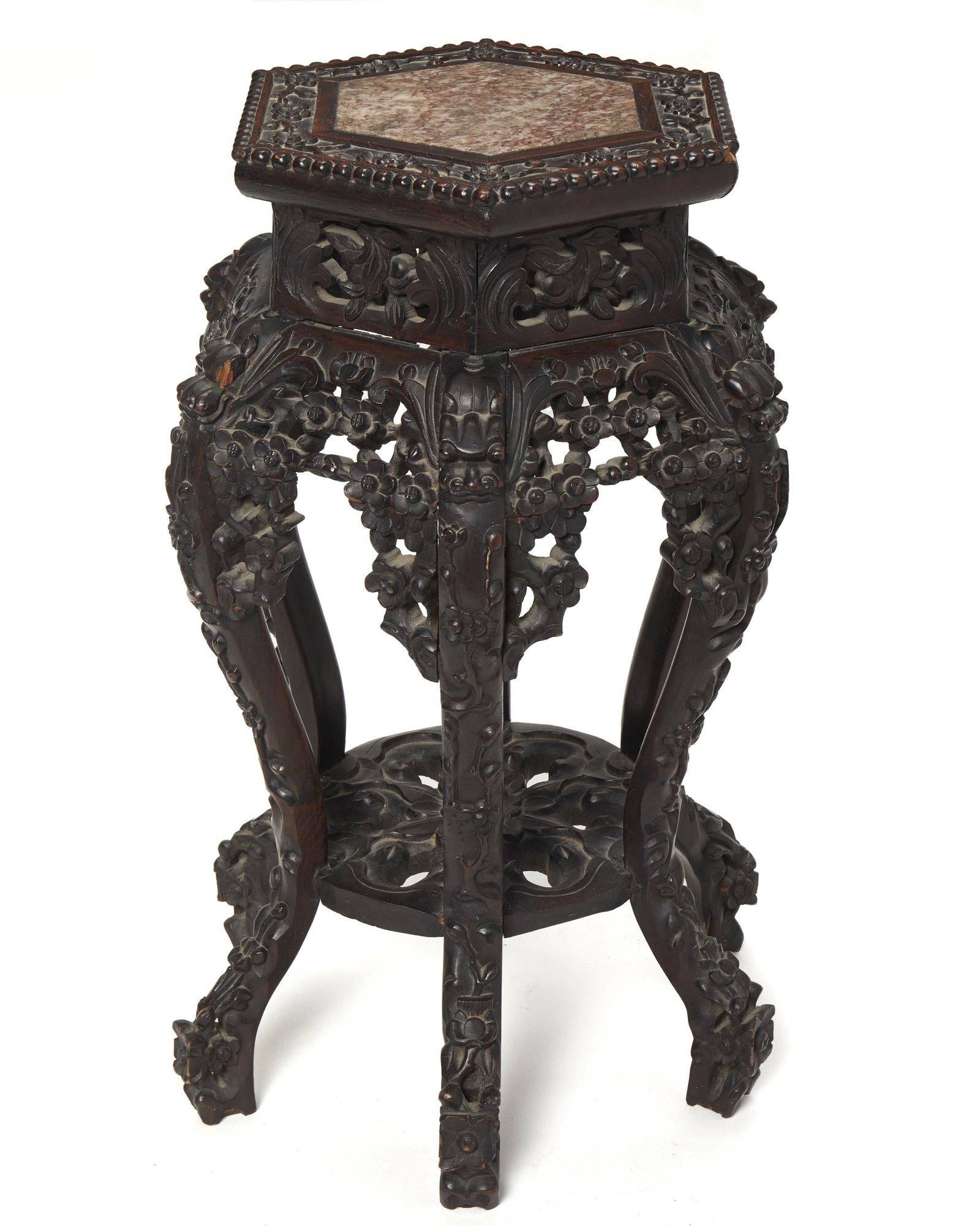 A Chinese carved wood stand: Late-19th/early-20th Century The inset marble top over carved hardwood apron with dogwood design and dragon shoulders with a craved floriform undershelf 28.25" H x 13.25" Dia.