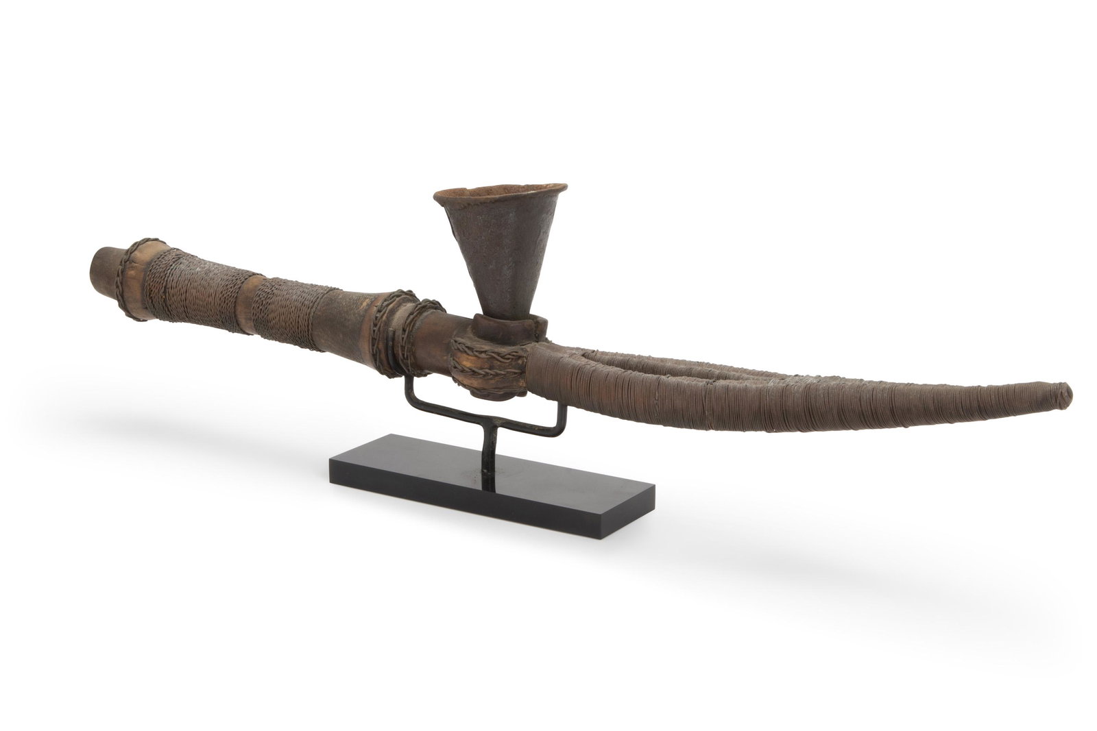 An African smoking pipe: Early-20th Century; Mahongwe culture, Gabon The long wooden pipe with braided brass threads and central section wrapped with wire and cast conical metal pipe bowl 2" H x 2" W x 20.5" D Provenance: Har