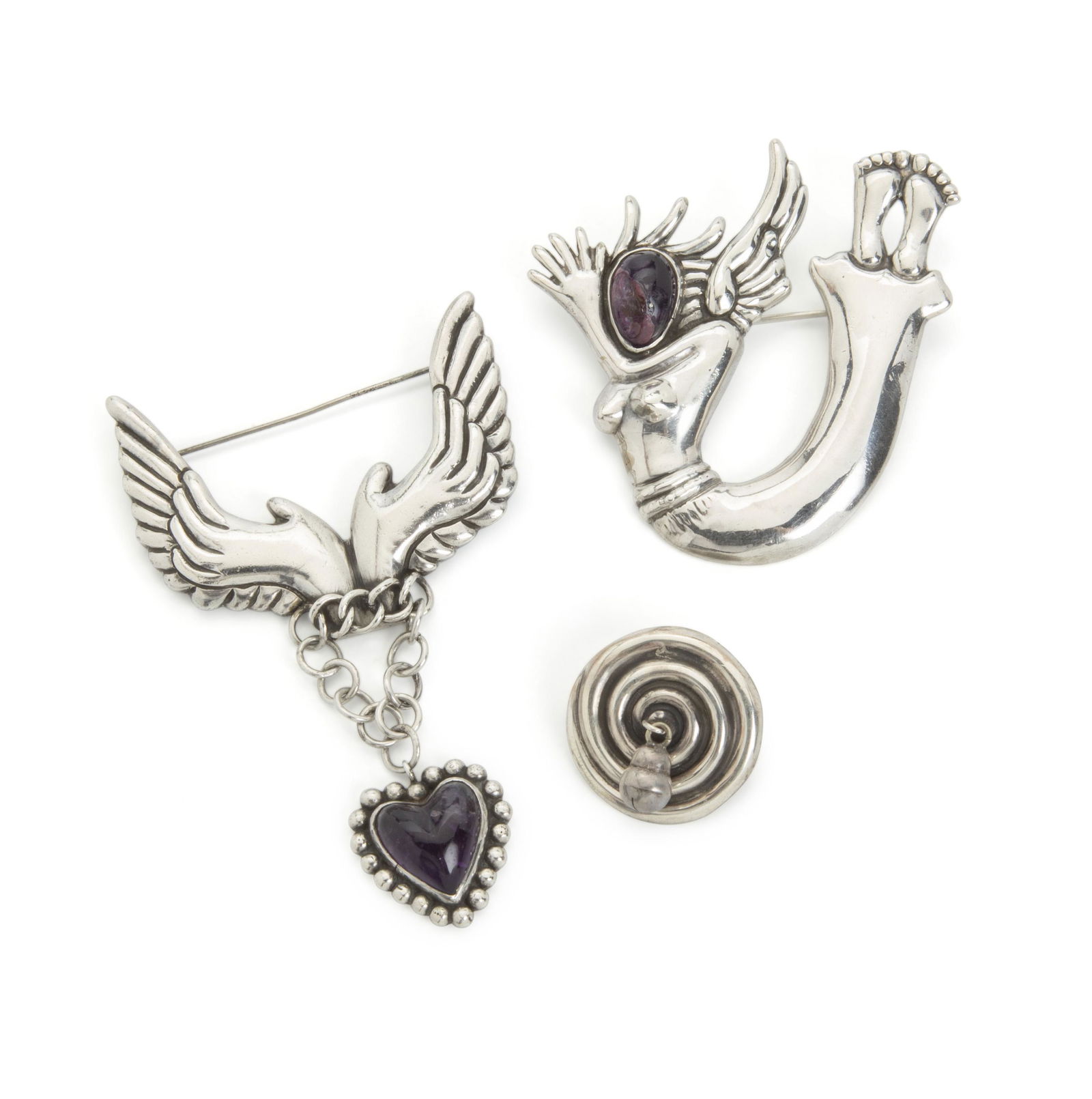 Three Hubert Harmon brooches: Circa 1940s; Taxco, Mexico Each stamped with feet mark for Hubert Harmon; Further stamped: Sterling / Hubert Harmon / Made in Mexico Comprising a hand and wing brooch suspending an amethyst-set hear